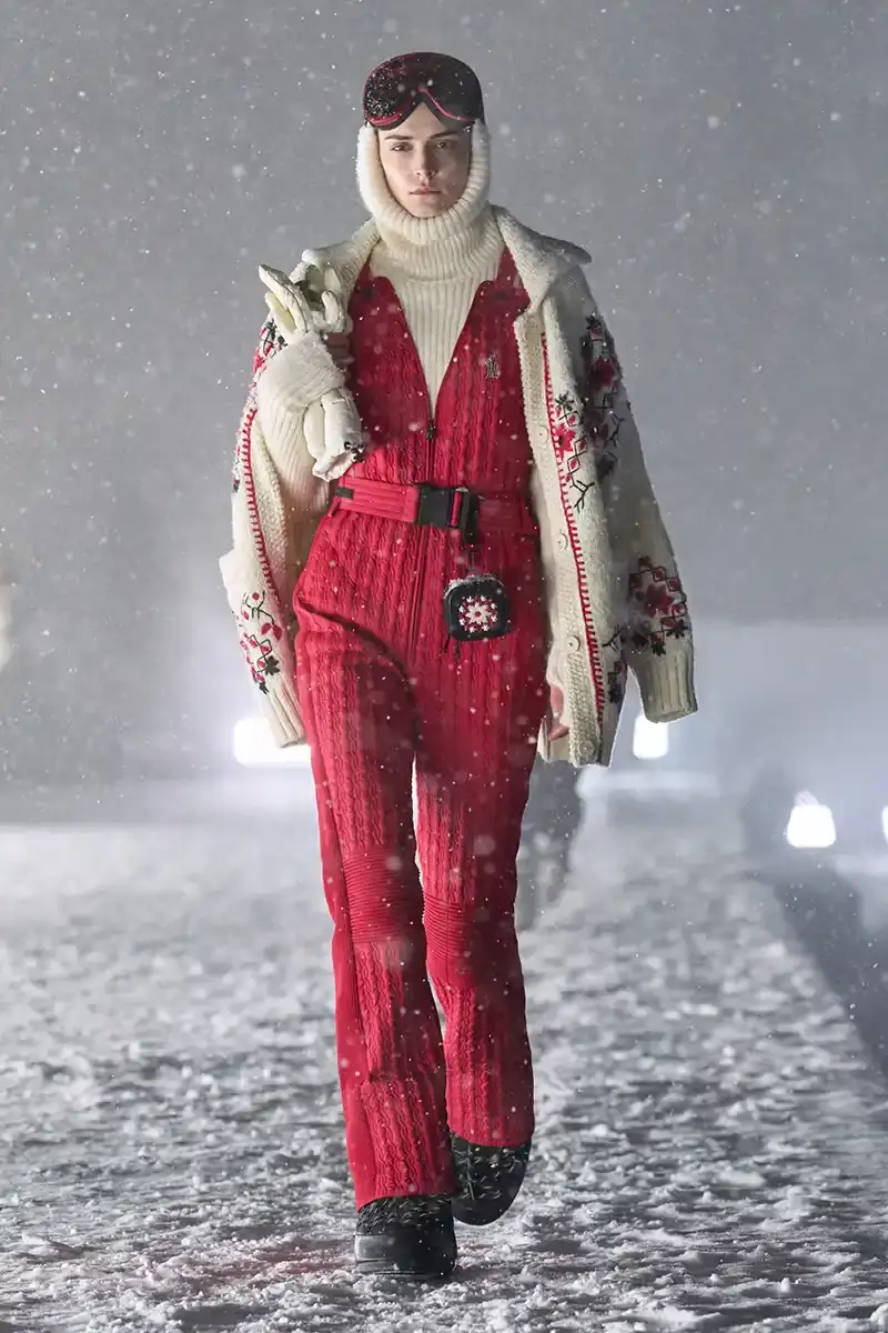 Moncler Moncler's Fall/Winter 2025 Grenoble collection showcase held at Courchevel Altiport in the French Alps. It details how the runway show transformed Europe's highest airport into a fashion venue at 2,008 meters above sea level. The article outlines the collection's 140 looks that blend urban style with mountain functionality, featuring innovative materials like denim and canvas alongside traditional winter textiles. It mentions the craftsmanship details including embroidery and intarsia patterns on ski suits. The article also notes celebrity attendees and a special snowboard collaboration with Shaun White's WHITESPACE brand. The content is organized in paragraphs describing the event setting, collection details, and notable highlights (image 19 of 22)
