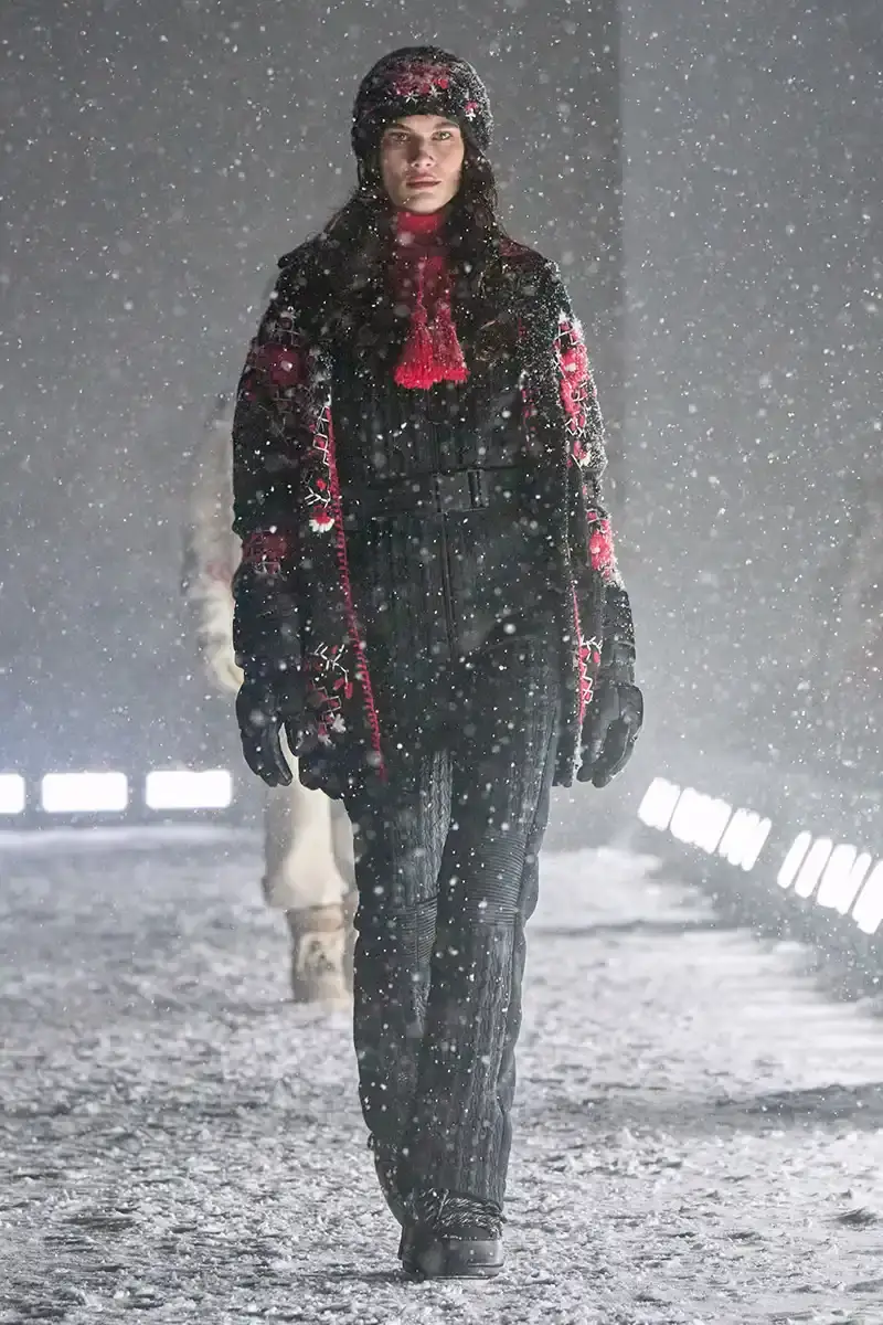 Moncler Moncler's Fall/Winter 2025 Grenoble collection showcase held at Courchevel Altiport in the French Alps. It details how the runway show transformed Europe's highest airport into a fashion venue at 2,008 meters above sea level. The article outlines the collection's 140 looks that blend urban style with mountain functionality, featuring innovative materials like denim and canvas alongside traditional winter textiles. It mentions the craftsmanship details including embroidery and intarsia patterns on ski suits. The article also notes celebrity attendees and a special snowboard collaboration with Shaun White's WHITESPACE brand. The content is organized in paragraphs describing the event setting, collection details, and notable highlights (image 17 of 22)