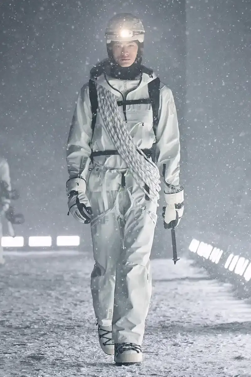 Moncler Moncler's Fall/Winter 2025 Grenoble collection showcase held at Courchevel Altiport in the French Alps. It details how the runway show transformed Europe's highest airport into a fashion venue at 2,008 meters above sea level. The article outlines the collection's 140 looks that blend urban style with mountain functionality, featuring innovative materials like denim and canvas alongside traditional winter textiles. It mentions the craftsmanship details including embroidery and intarsia patterns on ski suits. The article also notes celebrity attendees and a special snowboard collaboration with Shaun White's WHITESPACE brand. The content is organized in paragraphs describing the event setting, collection details, and notable highlights (image 21 of 22)