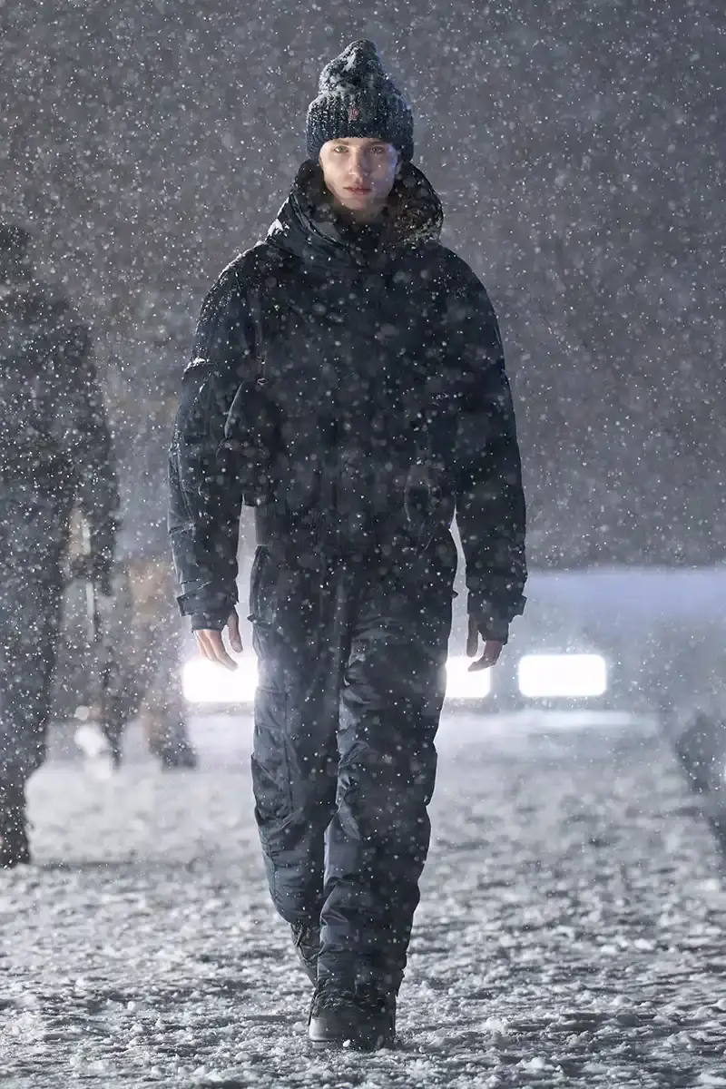 Moncler Moncler's Fall/Winter 2025 Grenoble collection showcase held at Courchevel Altiport in the French Alps. It details how the runway show transformed Europe's highest airport into a fashion venue at 2,008 meters above sea level. The article outlines the collection's 140 looks that blend urban style with mountain functionality, featuring innovative materials like denim and canvas alongside traditional winter textiles. It mentions the craftsmanship details including embroidery and intarsia patterns on ski suits. The article also notes celebrity attendees and a special snowboard collaboration with Shaun White's WHITESPACE brand. The content is organized in paragraphs describing the event setting, collection details, and notable highlights (image 10 of 22)