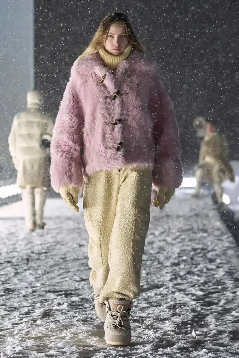 Moncler Moncler's Fall/Winter 2025 Grenoble collection showcase held at Courchevel Altiport in the French Alps. It details how the runway show transformed Europe's highest airport into a fashion venue at 2,008 meters above sea level. The article outlines the collection's 140 looks that blend urban style with mountain functionality, featuring innovative materials like denim and canvas alongside traditional winter textiles. It mentions the craftsmanship details including embroidery and intarsia patterns on ski suits. The article also notes celebrity attendees and a special snowboard collaboration with Shaun White's WHITESPACE brand. The content is organized in paragraphs describing the event setting, collection details, and notable highlights (image 13 of 22)