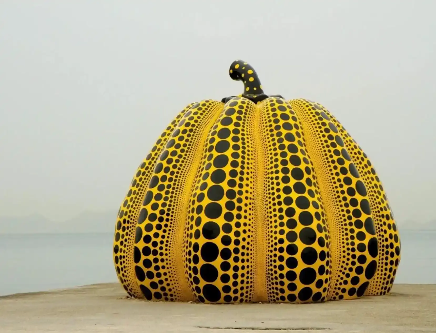 Artwork: Yayoi Kusama. Photo: Shigeo Anzai Yayoi Kusama's yellow pumpkin with black dots on a pier overlooking the sea