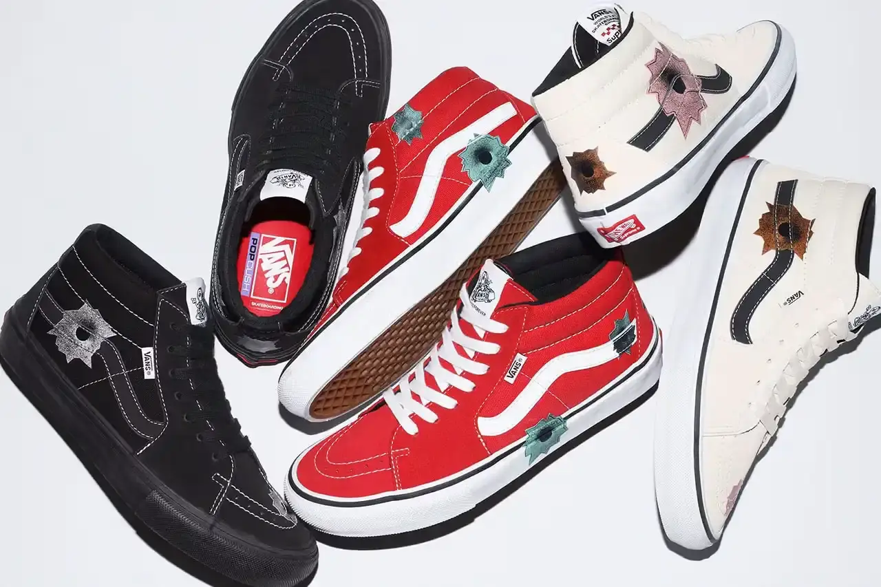 image of the release of a long-delayed collaboration between artist Nate Lowman, Supreme, and Vans. The Skate Grosso Mid sneaker features Lowman's signature bullet hole artwork on premium materials in three colorways: off-white, black, and red. Originally planned for 2022, the collection will finally release on April 26 exclusively at Supreme's Japanese stores and website, coinciding with Lowman's first solo exhibition in Japan titled "This Neighborhood's Changed." The article provides background on the collaborators' previous partnerships and details about the product design, including co-branding elements.