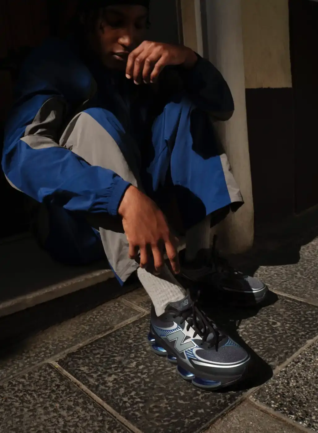 ENDRICK STARS IN NEW BALANCE ABZORB 2000 CAMPAIGN The header image displays Endrick standing on a street corner in Madrid while holding a grey and blue New Balance ABZORB 2000 sneaker. He wears a blue athletic tracksuit and looks down at the shoe in his hands. (image 4 of 4)