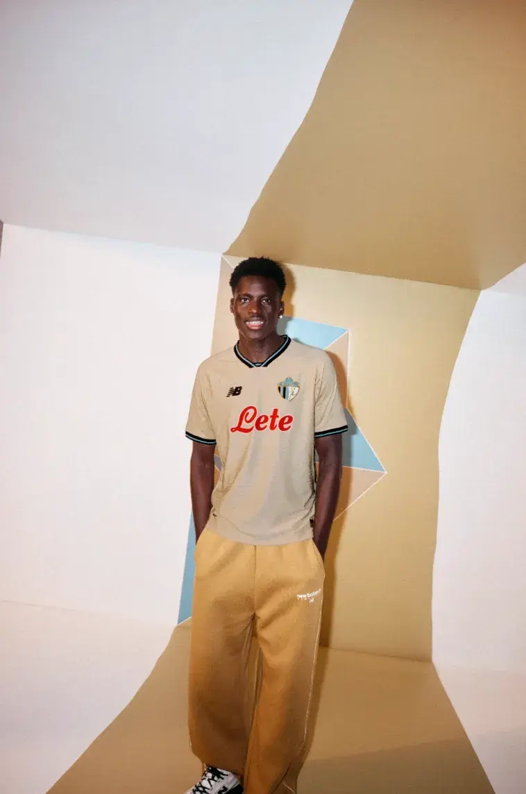 NEW BALANCE ATALANTA BC 2026/27 THIRD KIT image of A beige Atalanta BC football shirt with black and blue trim, featuring a gold 1964 logo and a geometric jacquard pattern. (image 4 of 4)