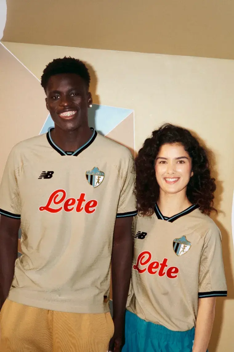NEW BALANCE ATALANTA BC 2026/27 THIRD KIT image of A beige Atalanta BC football shirt with black and blue trim, featuring a gold 1964 logo and a geometric jacquard pattern. (image 2 of 4)