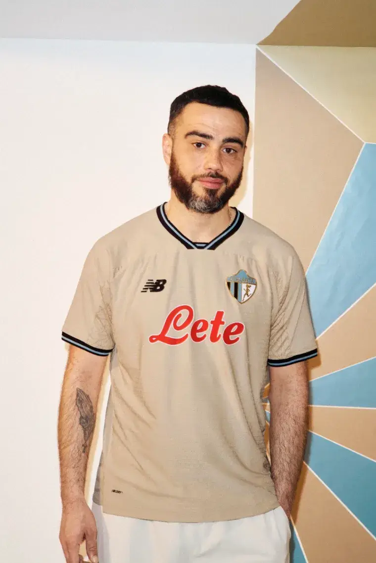 NEW BALANCE ATALANTA BC 2026/27 THIRD KIT image of A beige Atalanta BC football shirt with black and blue trim, featuring a gold 1964 logo and a geometric jacquard pattern. (image 3 of 4)