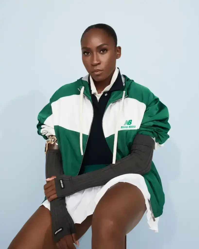 COCO GAUFF TO SPORT NEW BALANCE AND MIU MIU TENNIS COLLECTION image of collaboration between New Balance and Miu Miu featuring tennis champion Coco Gauff. It details how Gauff will wear the collection during tournaments in Rome, Berlin, and Cincinnati, describes the on-court outfits with color-block designs and co-branded Coco CG2 shoes, as well as off-court attire including zip hoodies and 530 SL sneakers. The collection launches September 10th at select stores and online, with Gauff hosting a Miu Miu Select event in New York the same day to showcase her personal picks from the Fall/Winter 2025 collection. (image 3 of 6)