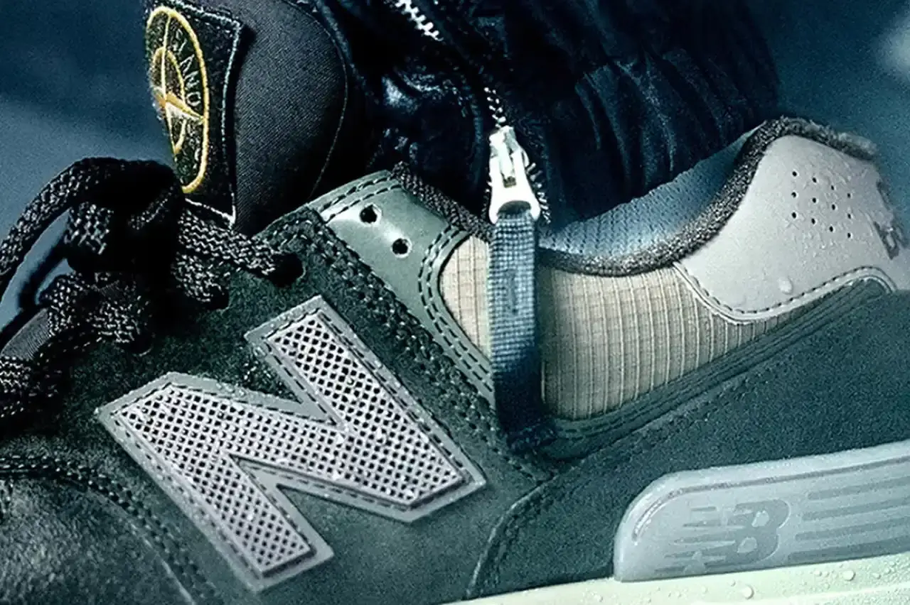 Stone Island and New Balance tease new collaboration. Image shows logos over trucks, with man pulling truck. Continues partnership since 2021, involving Tokyo Design Studio. Previous collaborations included RC Elite, 991v2, and 574 models. Suggests innovative sportswear design