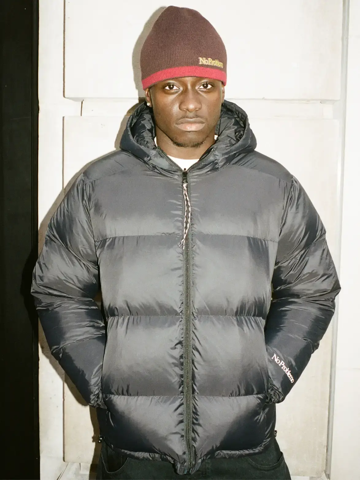 NO PROBLEMO AW26 COLLECTION DETAILS image of Two models wear No Problemo AW26 clothing. One wears a camouflage fleece and cap. The second person wears a blue striped long-sleeve polo shirt. (image 4 of 8)