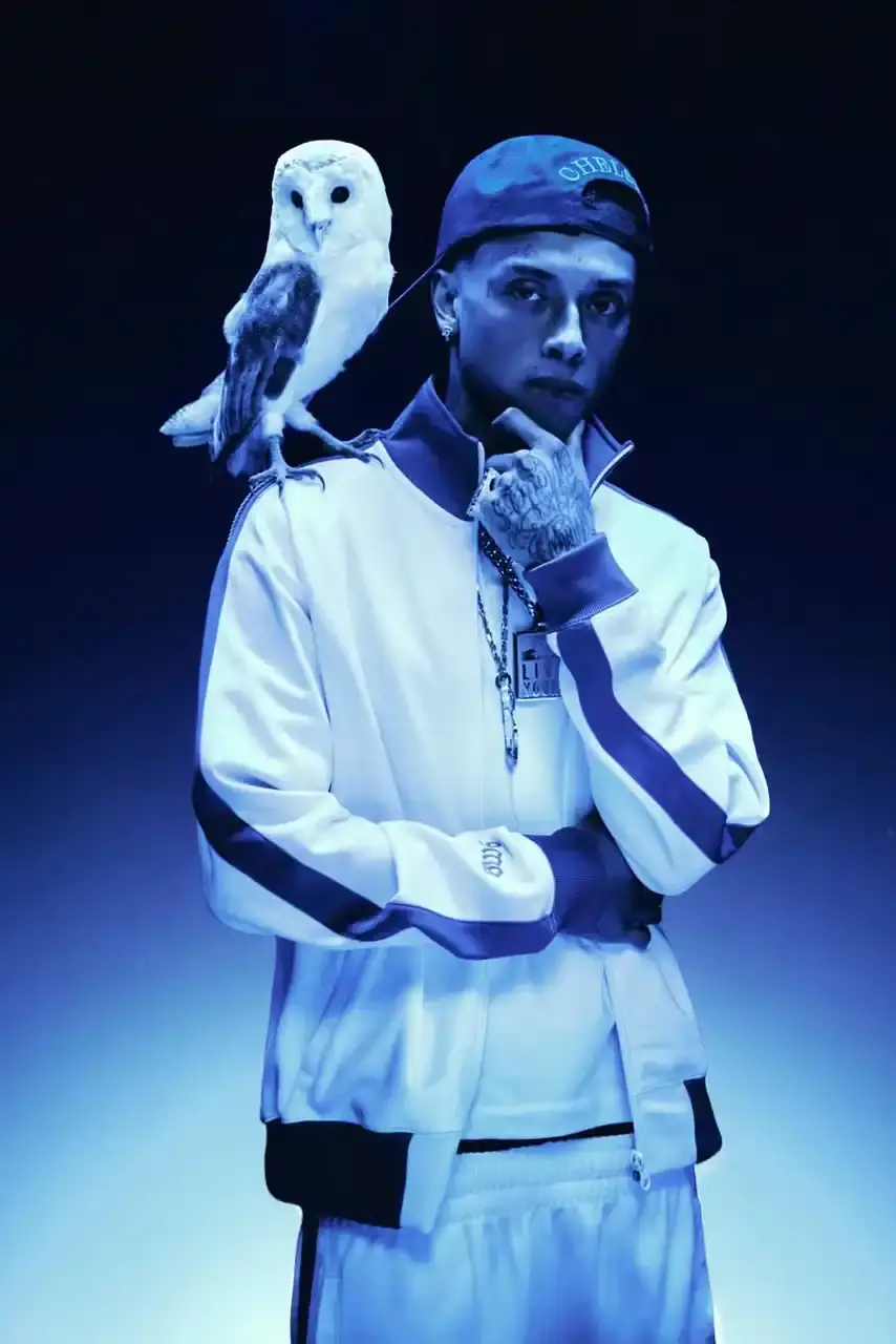 OVO PARTNERS WITH CHELSEA FC FOR LIMITED COLLECTION image about October's Very Own and Chelsea Football Club launching a collaborative clothing line. British rapper Central Cee models the collection which includes a varsity jacket, various shirts, hoodie and cap. The partnership combines Toronto streetwear culture with London football heritage through items featuring a merged OVO-Chelsea logo design.