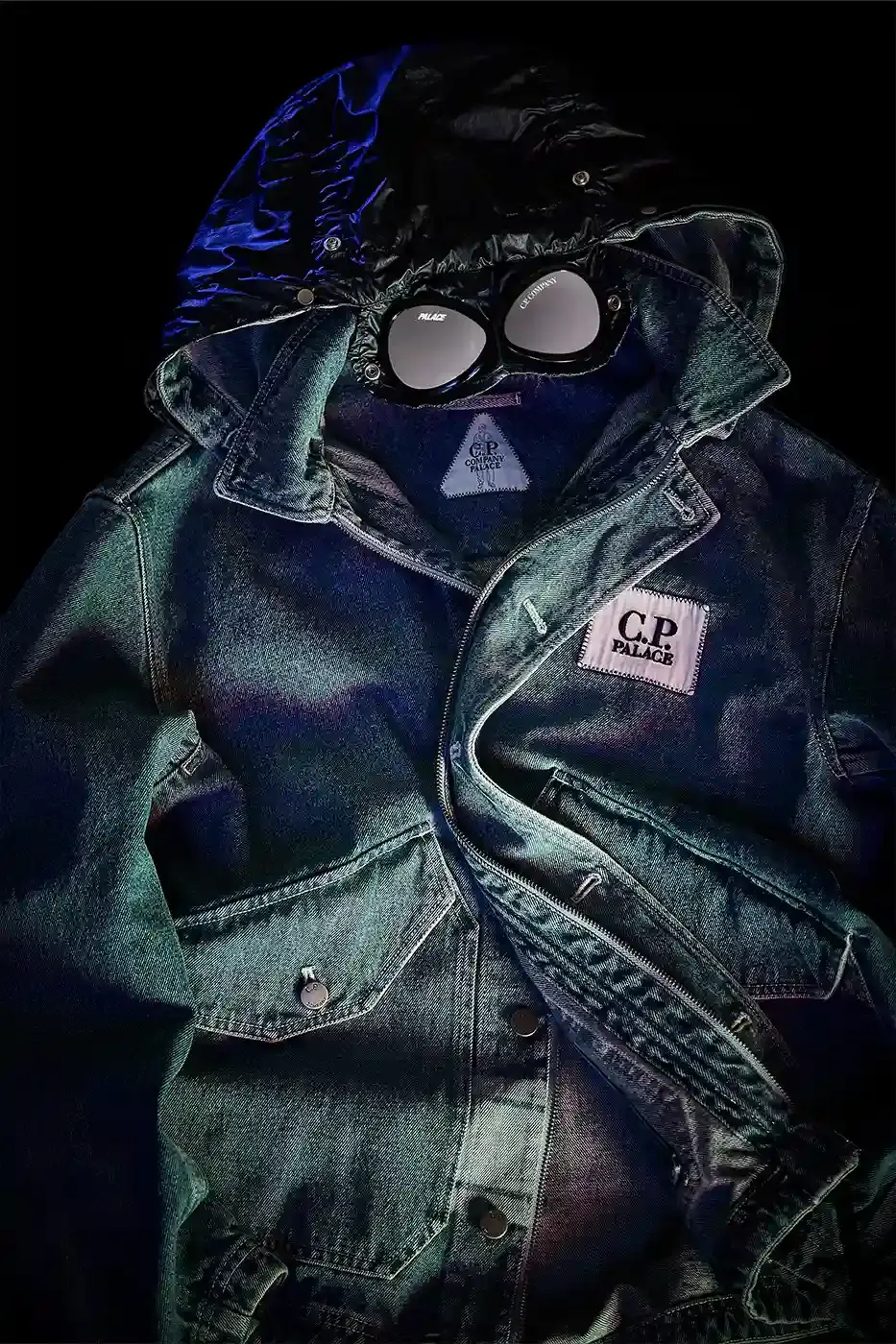 PALACE MEETS C.P. COMPANY: SKATE STYLE FUSES WITH ITALIAN CRAFT A fashion collaboration between Palace and C.P. Company. It details the "C.P. Palace" capsule collection featuring the Goggle Jacket, denim pieces, and various apparel in blue and khaki colors. The article provides information about the collection's availability starting March 28 at C.P. Company and Palace stores in multiple cities, plus a special pop-up at Dover Street Market Paris from March 28-30.