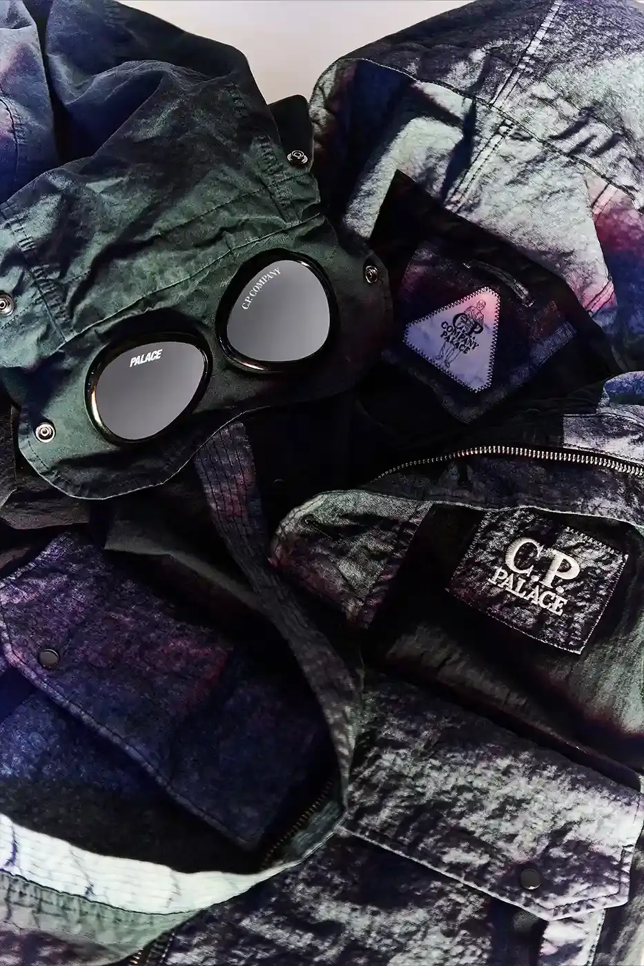 PALACE MEETS C.P. COMPANY: SKATE STYLE FUSES WITH ITALIAN CRAFT A fashion collaboration between Palace and C.P. Company. It details the "C.P. Palace" capsule collection featuring the Goggle Jacket, denim pieces, and various apparel in blue and khaki colors. The article provides information about the collection's availability starting March 28 at C.P. Company and Palace stores in multiple cities, plus a special pop-up at Dover Street Market Paris from March 28-30. (image 2 of 21)