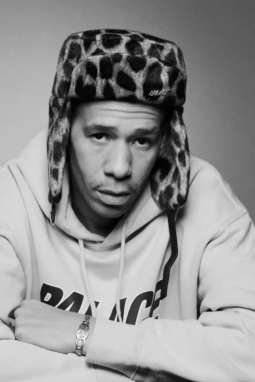 Palace Skateboards/Theo Sion Palace Spring 2025 lookbook showcasing a diverse collection of streetwear. Various models wear pieces including a tiger-embroidered varsity jacket, GORE-TEX outerwear, camouflage patterns, and racing-inspired jerseys. The collection features a mix of athletic and casual styles in multiple colorways, with detailed shots of snake graphics and workwear pieces (image 18 of 20)