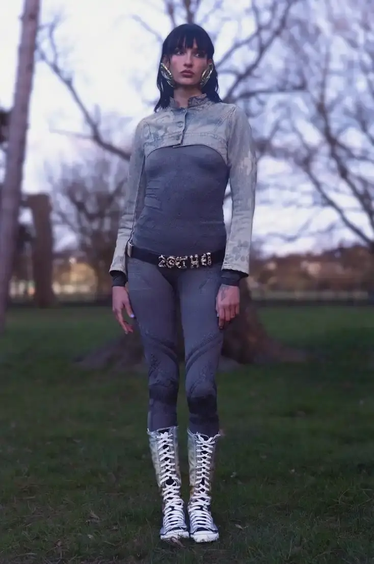 PAOLINA RUSSO'S AUTUMN-WINTER LINE BLENDS MEDIEVAL AND Y2K Photo of Paolina Russo's Autumn-Winter 2025 fashion collection, which combines medieval tailoring with early 2010s aesthetics. The collection features purple as a dominant color across various pieces, including denim, hoodies, and knits. Key elements include evolved "warrior knit" pieces, gold foil embellishments, and practical accessories like detachable hoods. The article also describes the designers' approach to merging traditional craftsmanship with modern technology, and mentions their recent industry recognitions including Forbes 30 under 30 and being finalists for prestigious fashion prizes. (image 6 of 12)
