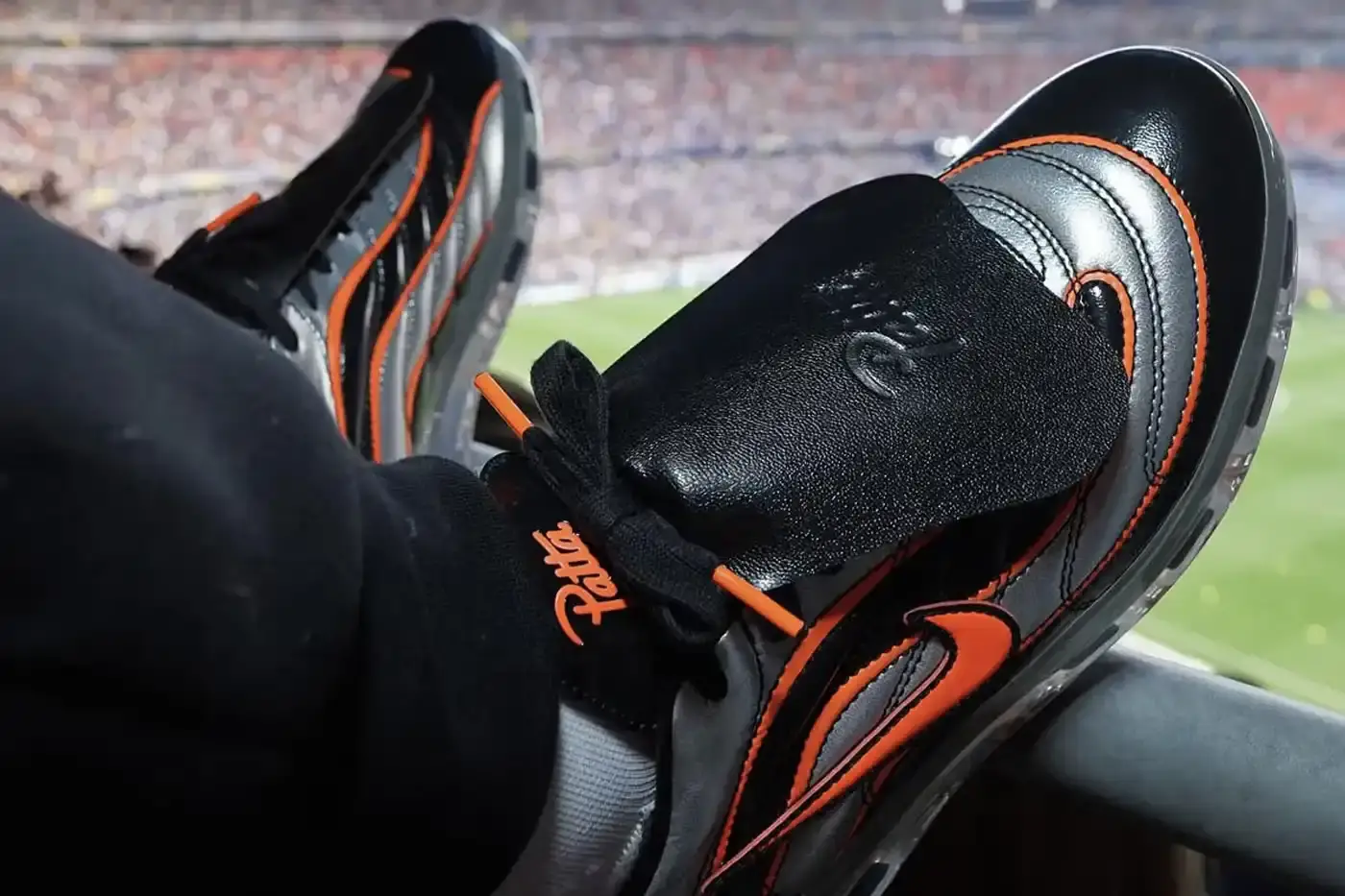 Article discusses the first preview of a collaborative sneaker between Amsterdam streetwear brand Patta and Nike. The shoe is based on Nike's new Cryoshot Mercurial design, which adapts football boots for casual wear. The Patta version uses a black and orange color scheme that references Dutch national colors, replacing the traditional blue and yellow Brazil colorway. The article includes details about the shoe's construction, branding placement, and technical features, while noting that no release date or pricing has been announced. This collaboration represents Nike's first partnership for their new Cryoshot series.