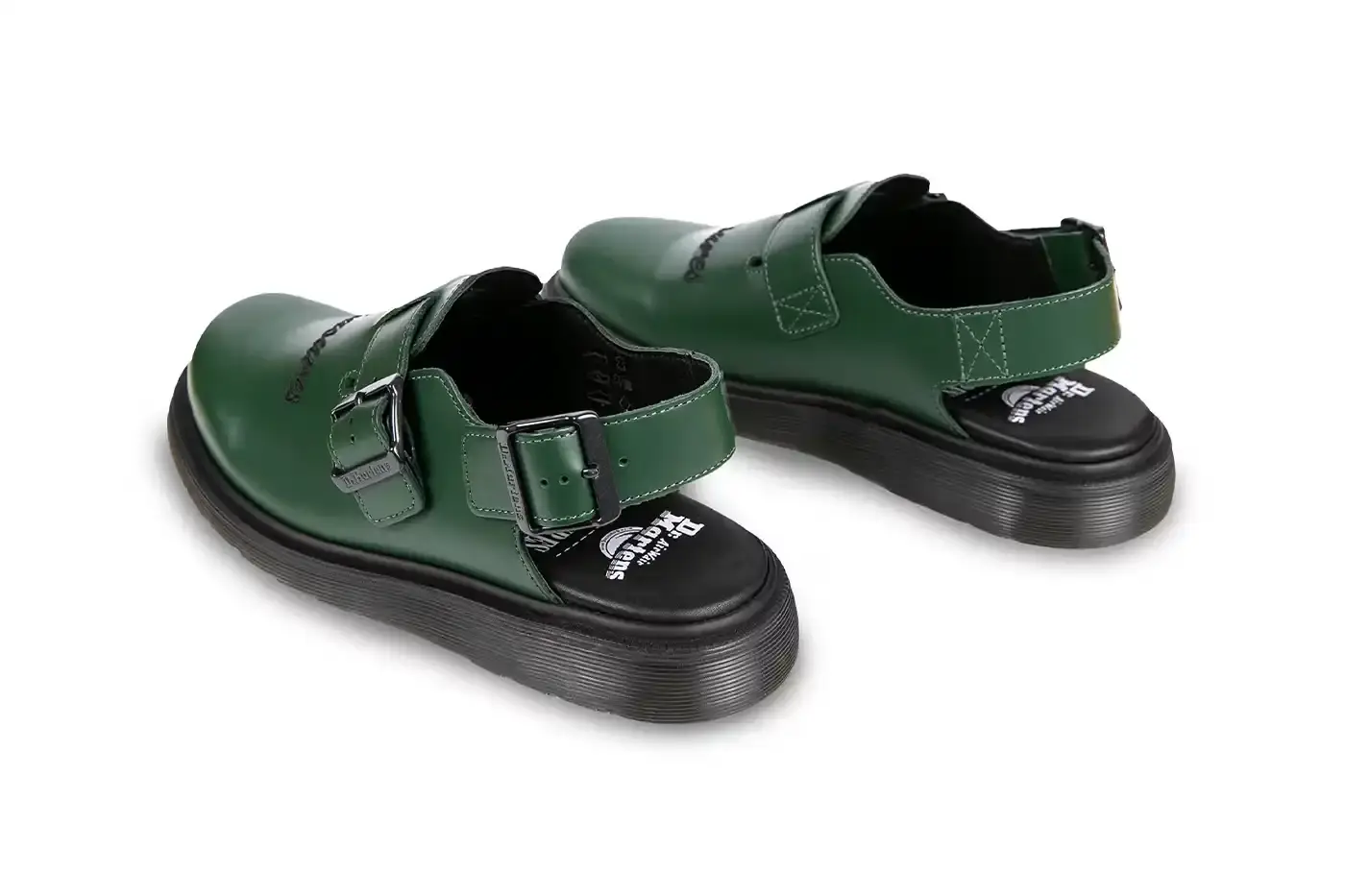 Ian Dooley/Pleasures Green leather Dr. Martens Jorge Mule featuring black metal buckles, cursive PLEASURES branding stitched on the upper, signature yellow stitching, and a black Vibram outsole. The collaboration merges both brands' distinctive styles in a versatile slip-on design. (image 6 of 11)