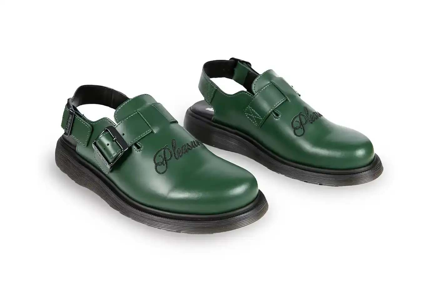 Ian Dooley/Pleasures Green leather Dr. Martens Jorge Mule featuring black metal buckles, cursive PLEASURES branding stitched on the upper, signature yellow stitching, and a black Vibram outsole. The collaboration merges both brands' distinctive styles in a versatile slip-on design. (image 4 of 11)