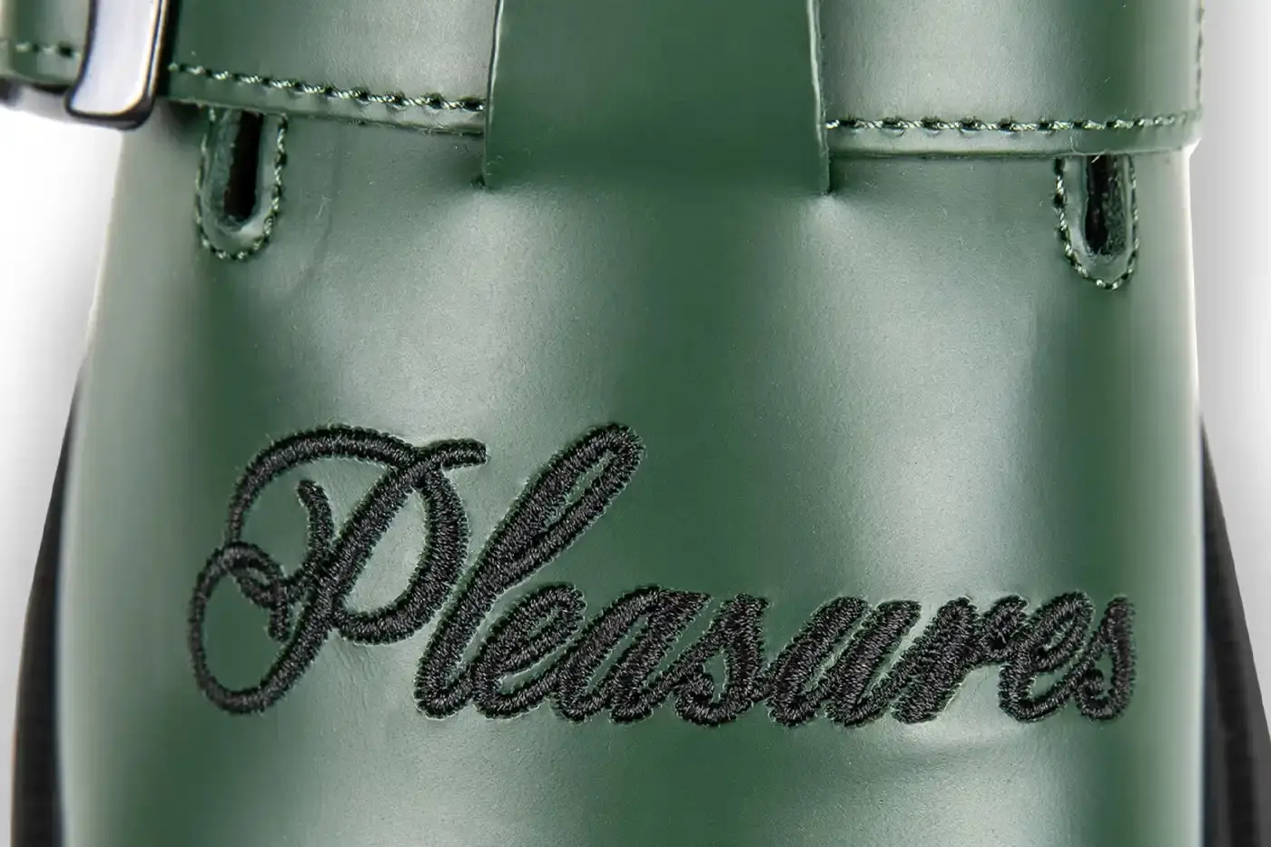 Ian Dooley/Pleasures Green leather Dr. Martens Jorge Mule featuring black metal buckles, cursive PLEASURES branding stitched on the upper, signature yellow stitching, and a black Vibram outsole. The collaboration merges both brands' distinctive styles in a versatile slip-on design. (image 8 of 11)