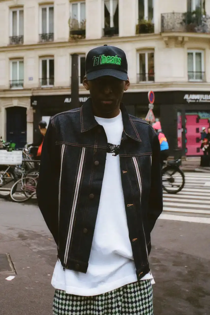 Quinn Dunziellas PLEASURES Spring/Summer 2025 lookbook photograph showcases models wearing the new collection against Parisian backdrops. Featured items include a Realtree camo jacket, leopard print blazer, and holographic-lined outerwear pieces.