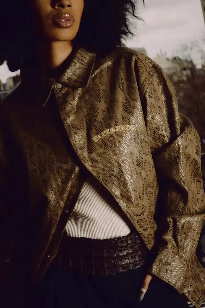 Quinn Dunziellas PLEASURES Spring/Summer 2025 lookbook photograph showcases models wearing the new collection against Parisian backdrops. Featured items include a Realtree camo jacket, leopard print blazer, and holographic-lined outerwear pieces. (image 7 of 15)