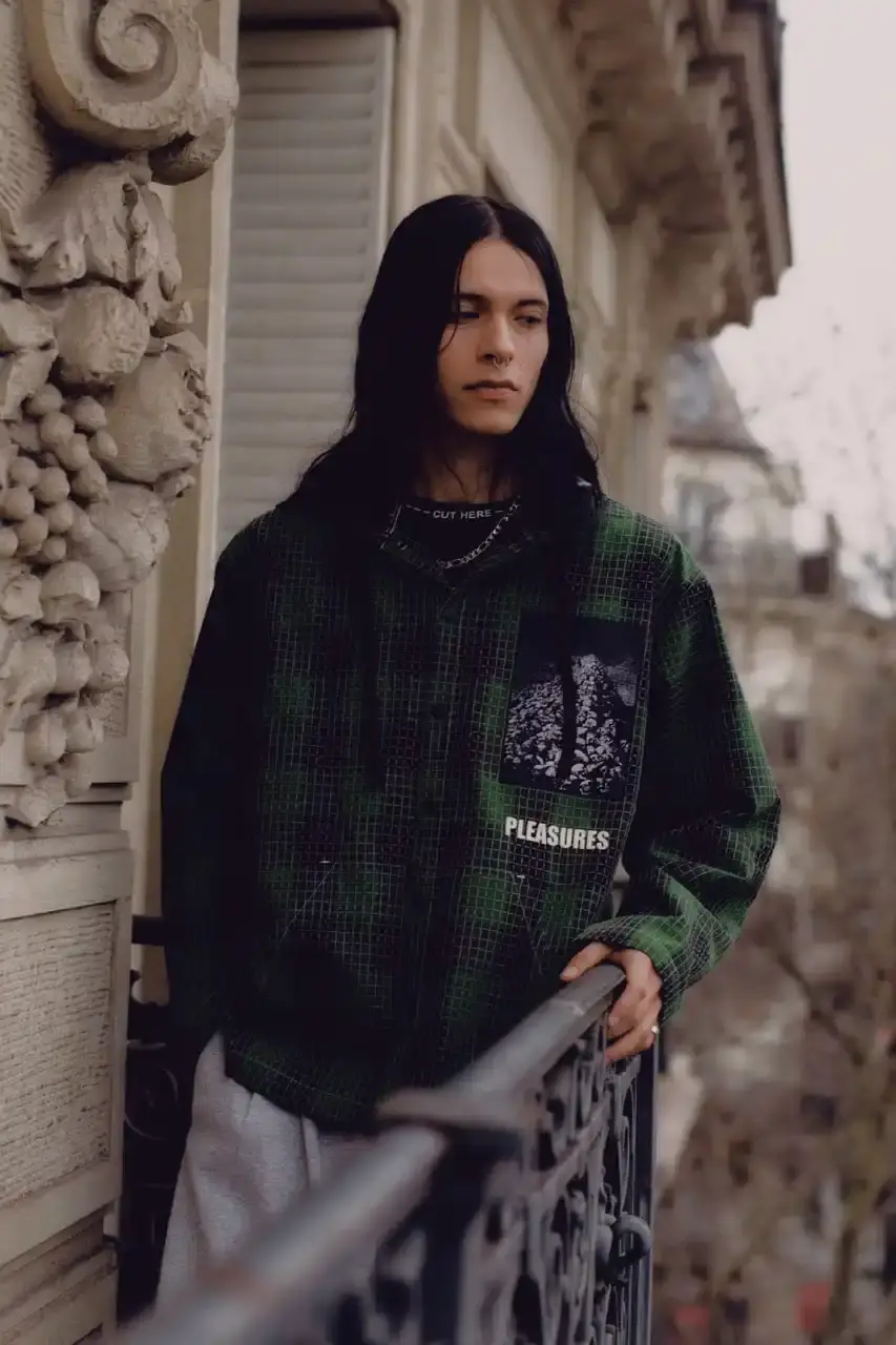 Quinn Dunziellas PLEASURES Spring/Summer 2025 lookbook photograph showcases models wearing the new collection against Parisian backdrops. Featured items include a Realtree camo jacket, leopard print blazer, and holographic-lined outerwear pieces. (image 12 of 15)