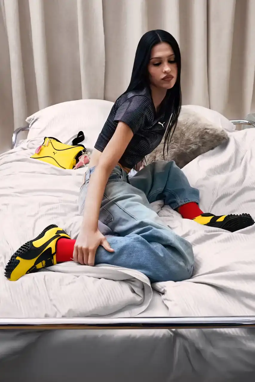PUMA MOSTRO RETURNS IN PELÉ YELLOW WITH AMELIA GRAY image of PUMA's latest Mostro sneaker release in yellow colorway, featuring model Amelia Gray in promotional campaign imagery. Includes product specifications, pricing at $120 USD, and June 5 release date through PUMA retail channels. (image 2 of 7)