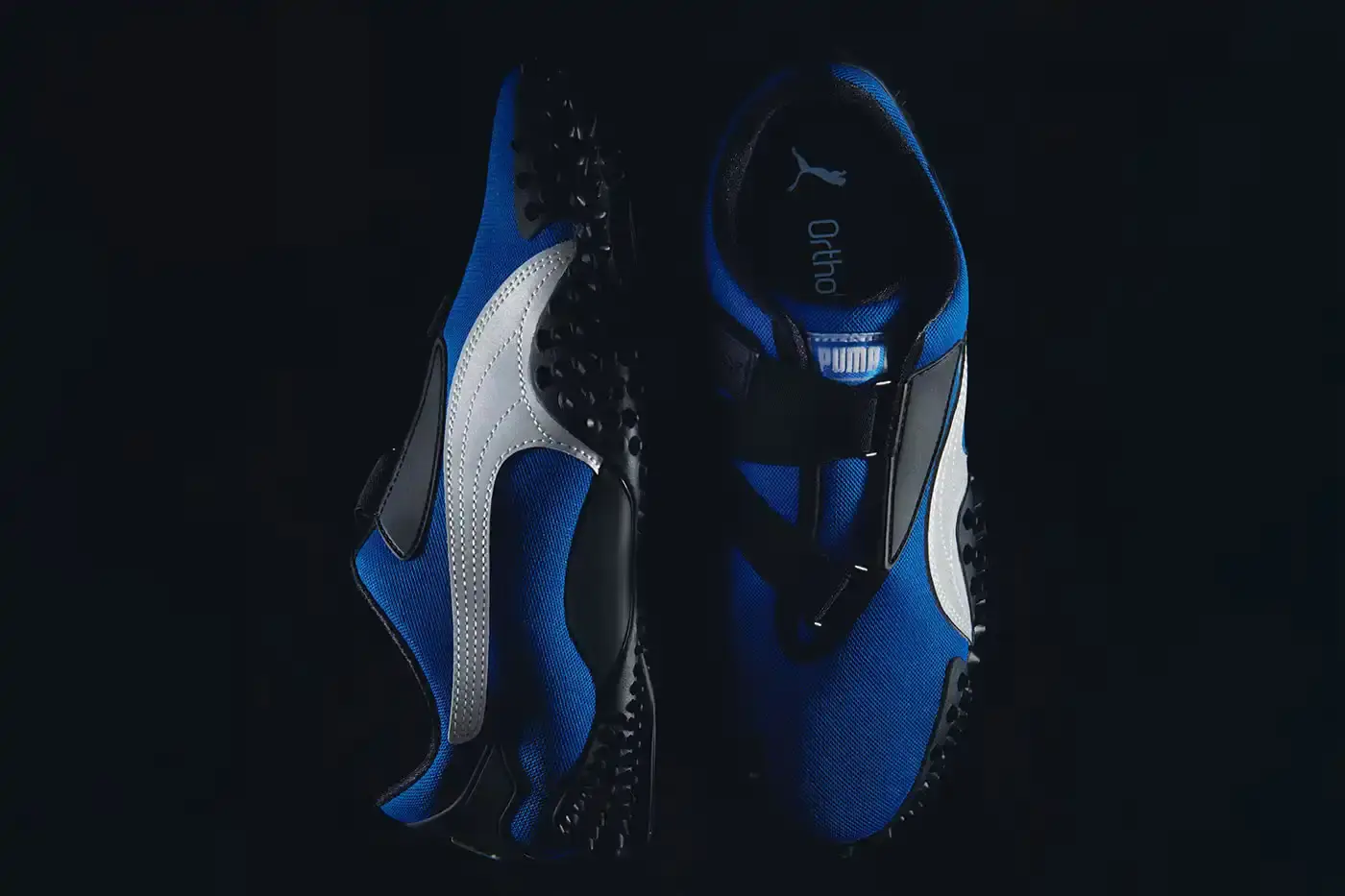 Puma PUMA Mostro OG sneakers displayed in three colorways - Team Royal blue with silver accents, Green Moon green with silver detailing, and All Time Red with silver trim. Each shoe features the model's distinctive spiked sole, mesh upper, and hook-and-loop fastening system. (image 3 of 8)