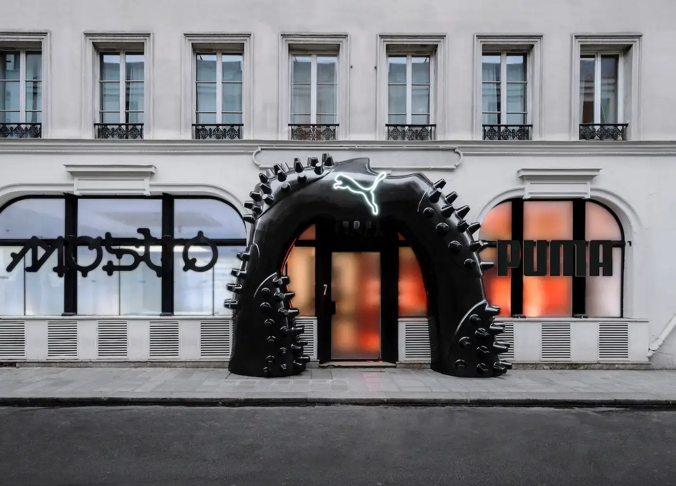Puma Image shows PUMA's Paris Fashion Week event promotional visual, highlighting collaborative design, urban culture, and the Mostro sneaker with diverse creative elements in the background.