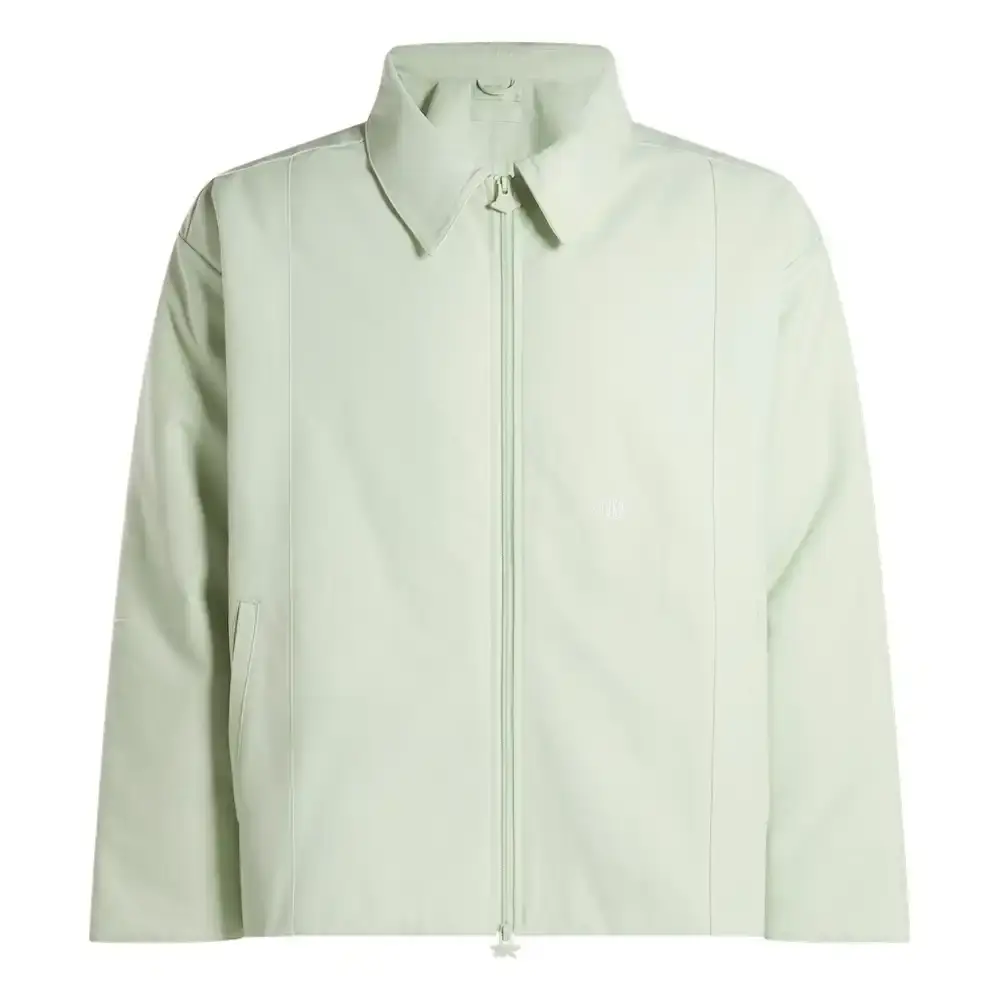 Reebok Tobe Nwigwe wearing a mint green coach jacket and black pants from the Reebok x Chukwu collection, standing next to the Chukwu OTU sneaker (image 9 of 9)