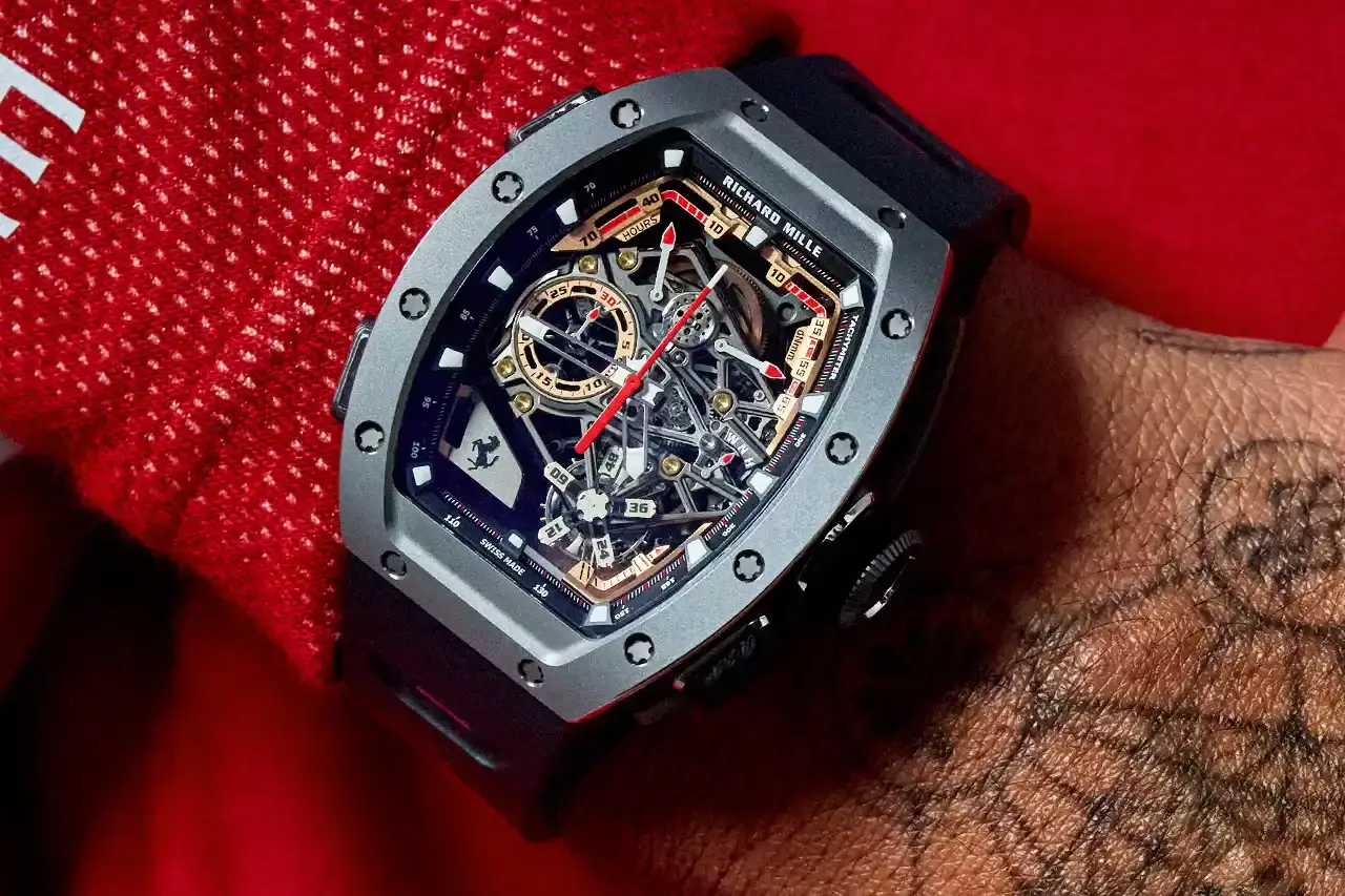 PRECISION MECHANICS: RICHARD MILLE'S FERRARI TRIBUTE WATCH A collaborative watch between Richard Mille and Ferrari, highlighting its design, technological features, and automotive-inspired elements. The text provides a comprehensive overview of the RM 43-01 Tourbillon Split-Seconds Chronograph, detailing its mechanical specifications, design influences from Ferrari's Centro Stile, and limited edition variants. The description covers technical aspects such as power reserve, movement design, and aesthetic connections to Ferrari's automotive heritage, making the complex watch design accessible to readers with varying levels of horological expertise. (image 2 of 7)