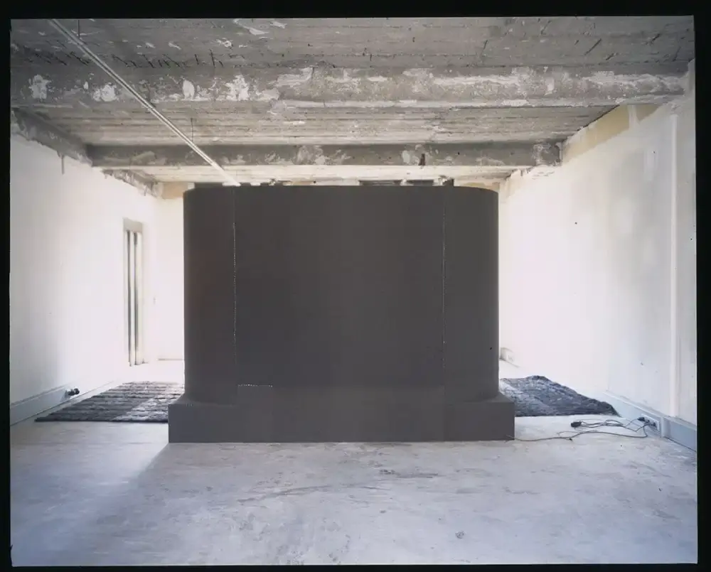Assaf Shoshan/PIN–UP Interior of Rick Owens' brutalist Parisian home featuring unpolished floors, exposed wiring, a platform bed with Swiss Army blankets, and minimalist furnishings. (image 2 of 6)