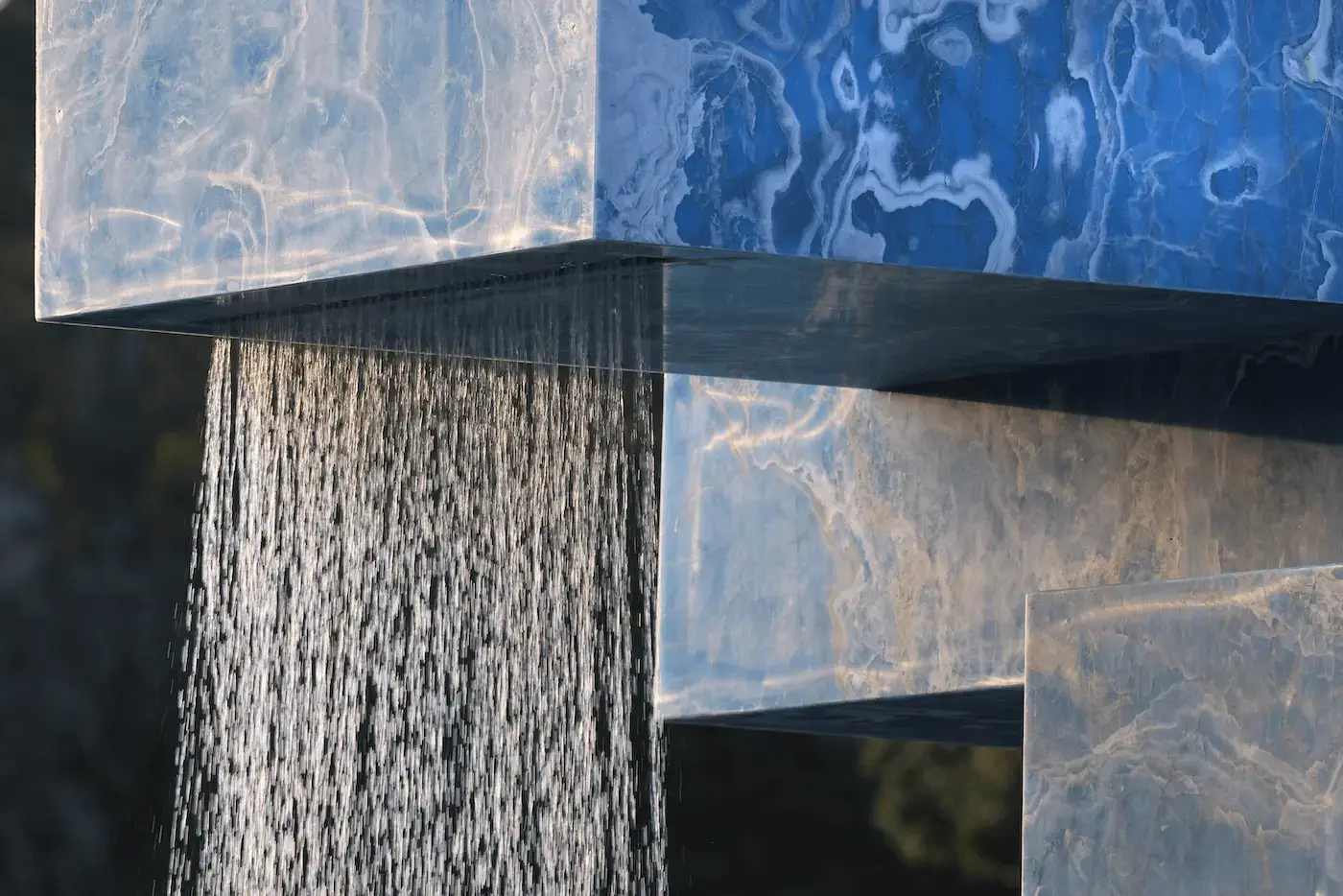 SABINE MARCELIS' ONYX FOUNTAIN TRANSFORMS VONDELPARK IN AMSTERDAM Vondel Fountain, Stacked: A large, striking fountain made of stacked, recycled onyx slabs located in one of the lakes in Amsterdam's Vondelpark. Water cascades from two sides, creating a soothing, relaxing sound (image 5 of 7)