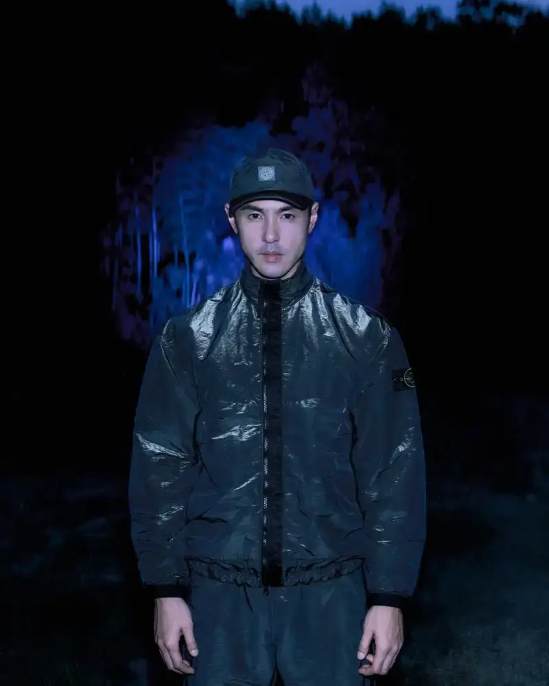 STONE ISLAND LUNAR NEW YEAR HORSE COLLECTION Stone Island introduces a Lunar New Year collection for the Year of the Horse, featuring a stand collar jacket, joggers, cap, and sling bag in NYLON METAL fabric with gold and dark brown colors. (image 9 of 10)