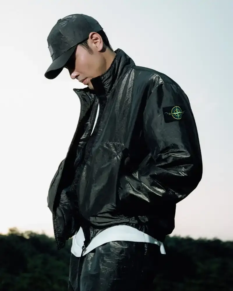 STONE ISLAND LUNAR NEW YEAR HORSE COLLECTION Stone Island introduces a Lunar New Year collection for the Year of the Horse, featuring a stand collar jacket, joggers, cap, and sling bag in NYLON METAL fabric with gold and dark brown colors. (image 7 of 10)