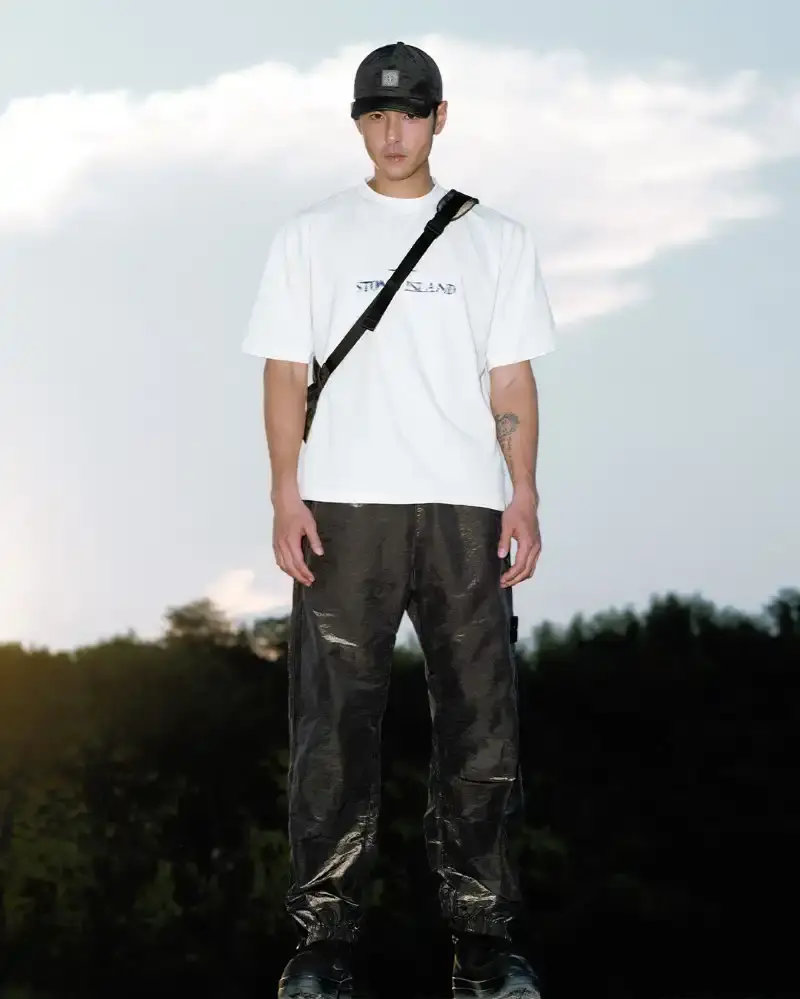 STONE ISLAND LUNAR NEW YEAR HORSE COLLECTION Stone Island introduces a Lunar New Year collection for the Year of the Horse, featuring a stand collar jacket, joggers, cap, and sling bag in NYLON METAL fabric with gold and dark brown colors. (image 8 of 10)