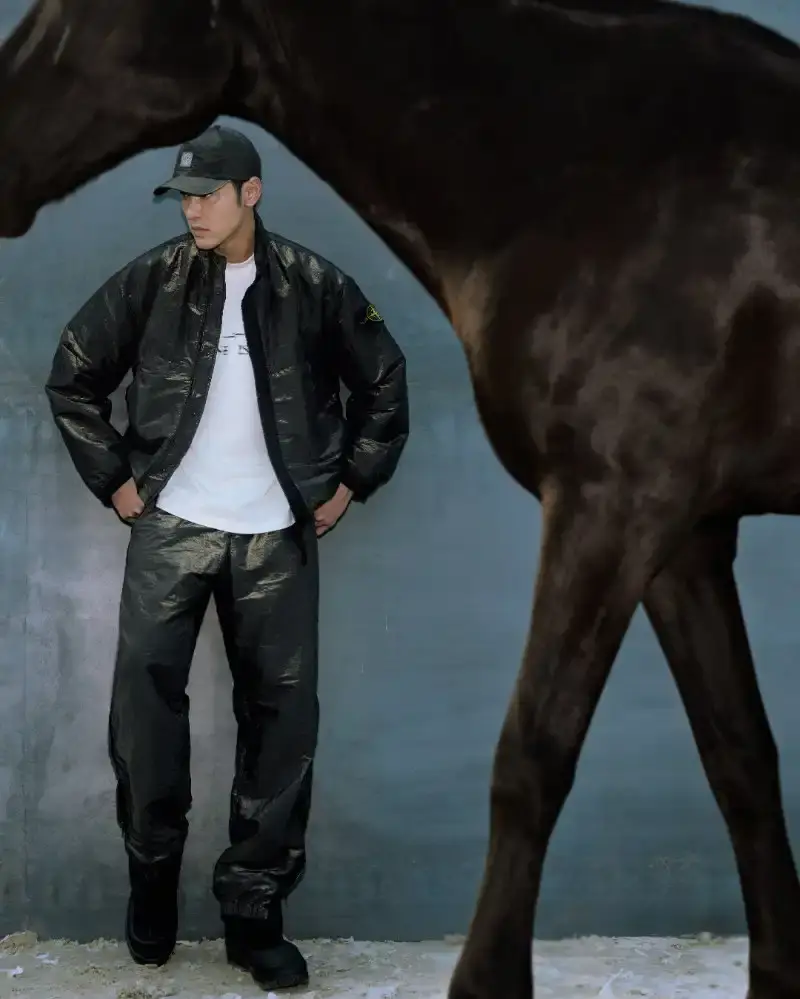 STONE ISLAND LUNAR NEW YEAR HORSE COLLECTION Stone Island introduces a Lunar New Year collection for the Year of the Horse, featuring a stand collar jacket, joggers, cap, and sling bag in NYLON METAL fabric with gold and dark brown colors. (image 4 of 10)