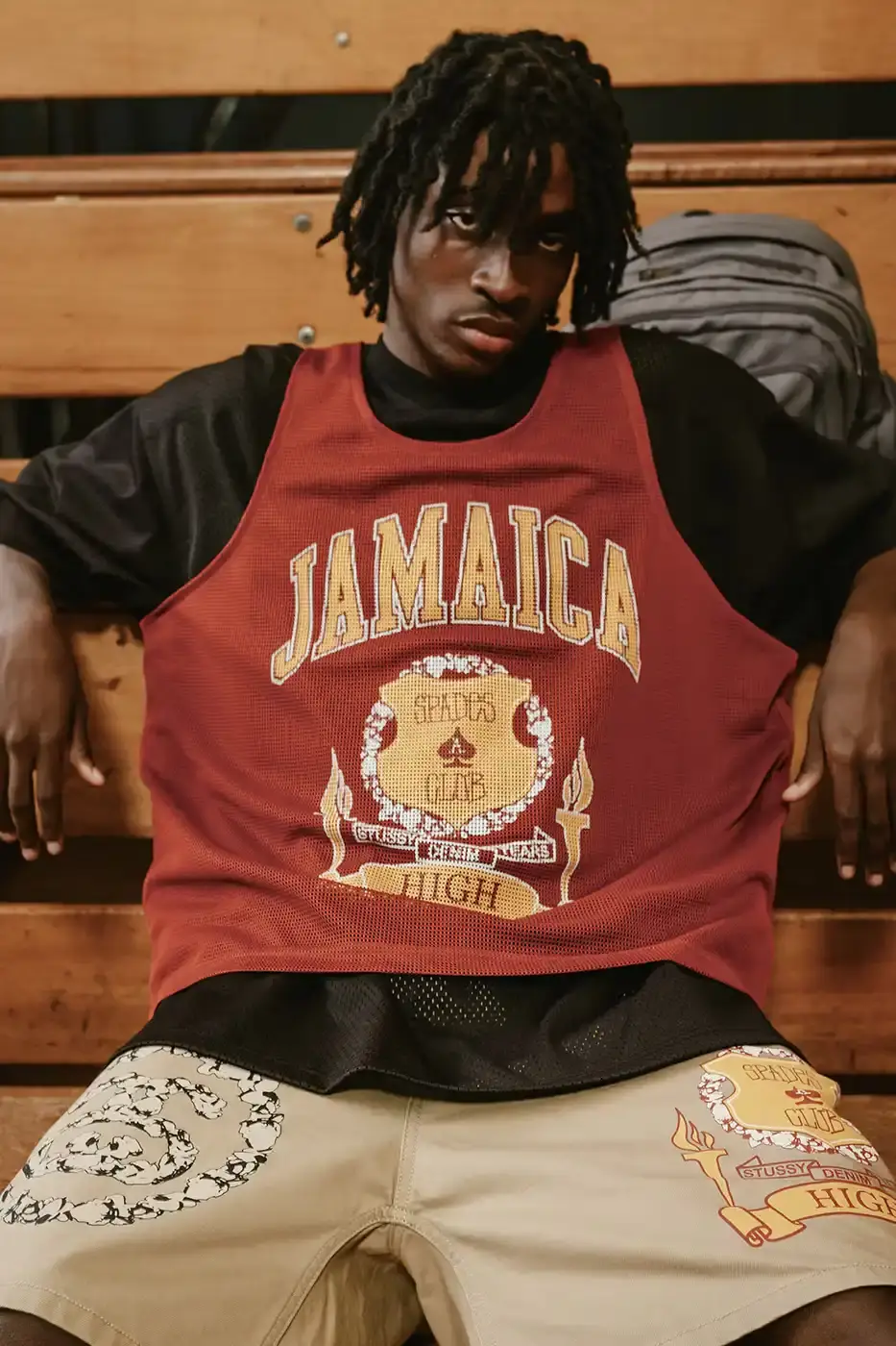Stüssy/Denim Tears A display of Stüssy x Denim Tears' school-inspired collection, showing oxford shirts, blazers, and chinos arranged on a neutral background. The pieces feature co-branded designs and Pan-African American flag motifs. (image 3 of 11)