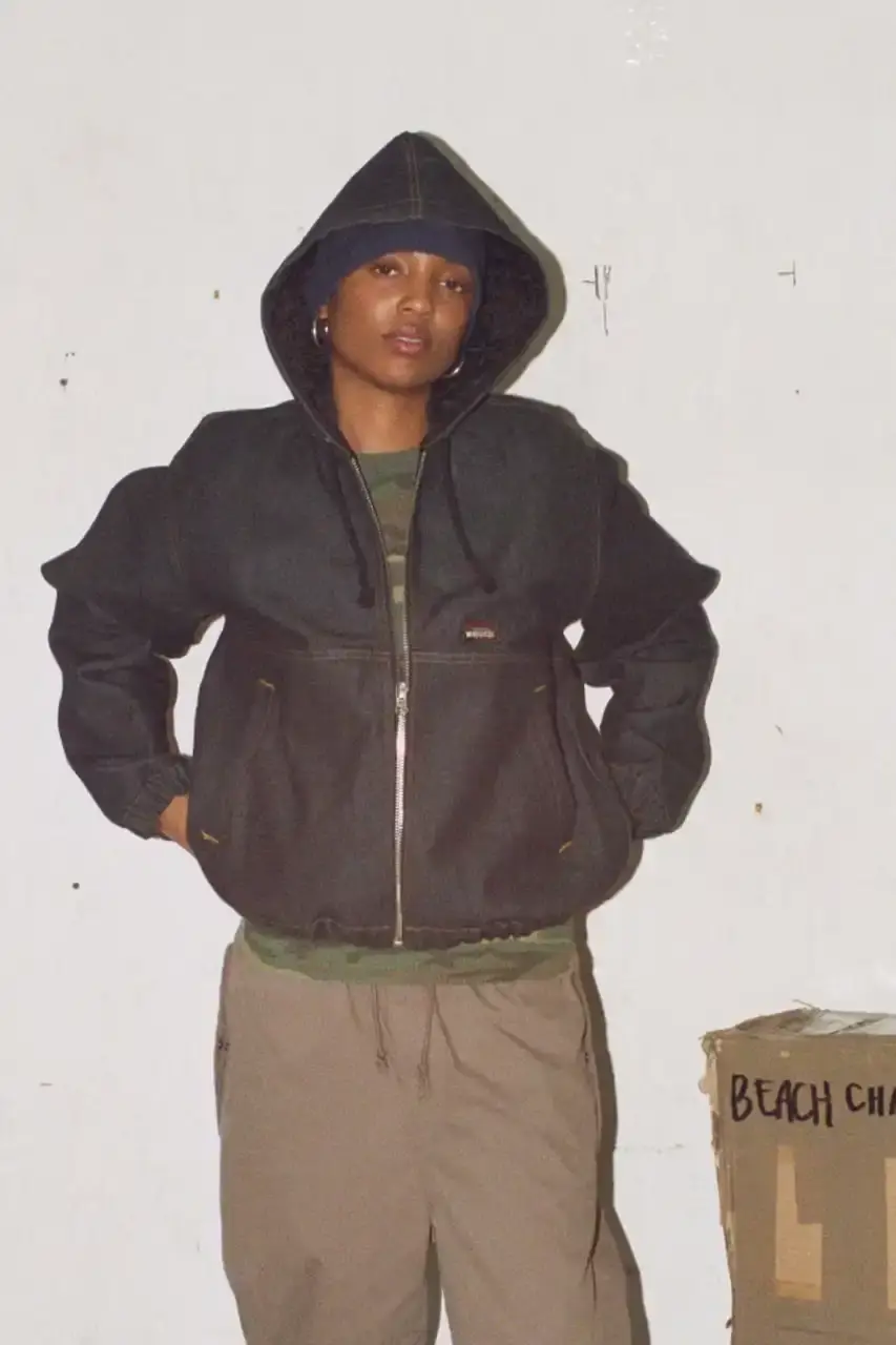 Antosh Cimoszko Stüssy Spring 2025 collection lookbook featuring an urban model wearing an oversized camouflage jacket, baggy denim trousers, and wide-cut shorts in muted green and blue tones. (image 3 of 26)
