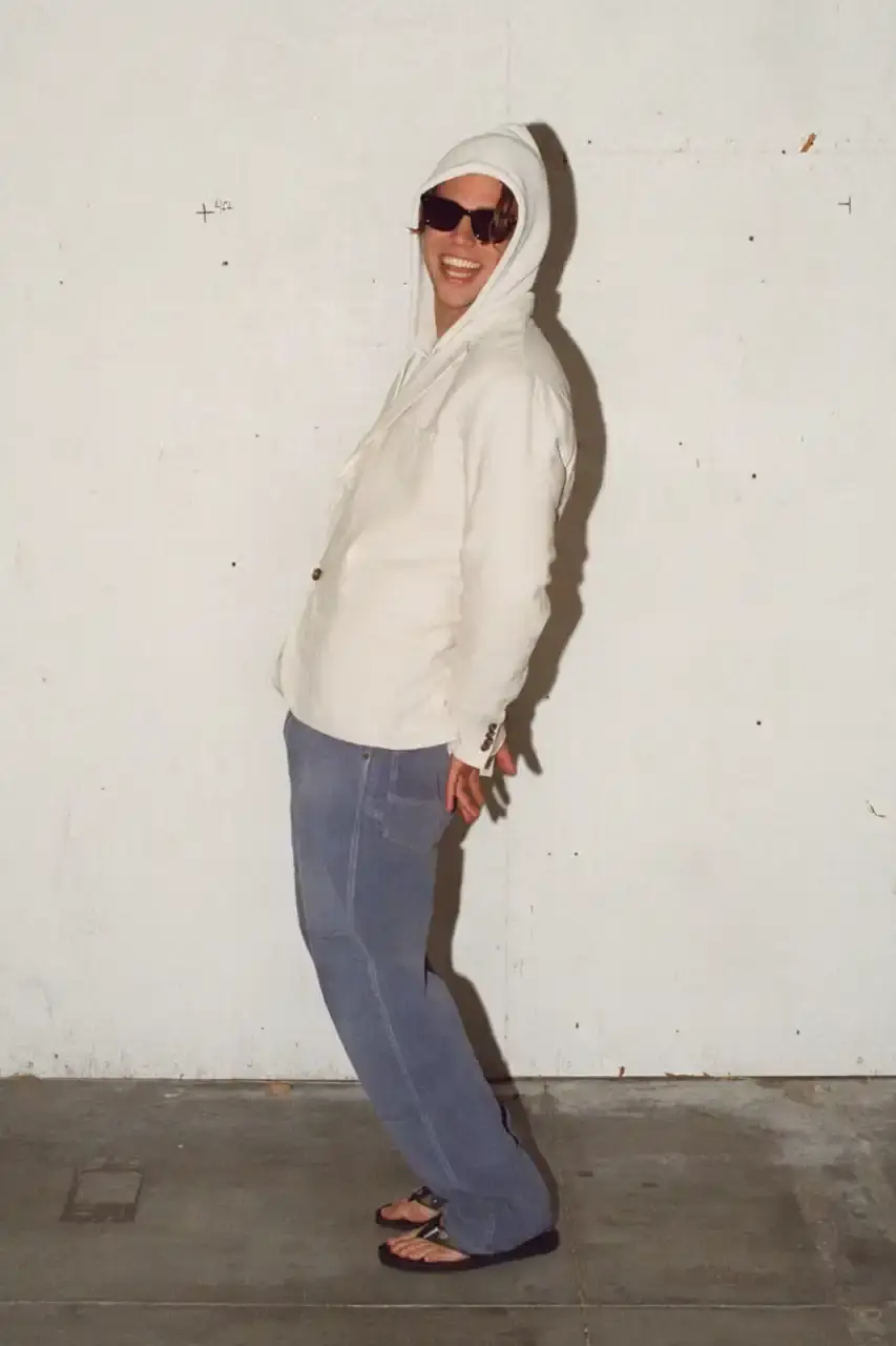 Antosh Cimoszko Stüssy Spring 2025 collection lookbook featuring an urban model wearing an oversized camouflage jacket, baggy denim trousers, and wide-cut shorts in muted green and blue tones.