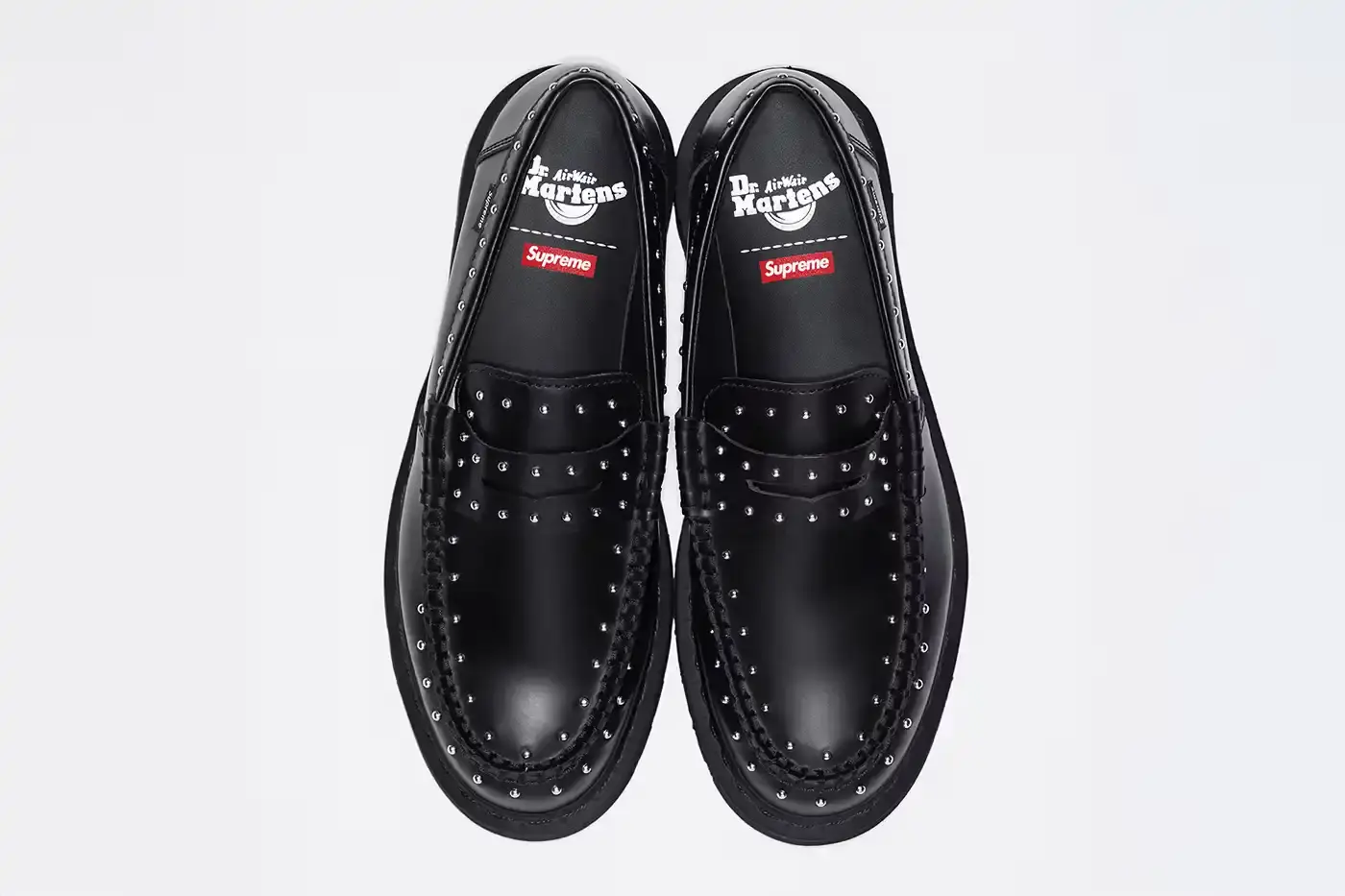 image of the Spring 2025 collaboration between Supreme and Dr. Martens featuring Studded Penton Loafers. The piece describes the three colorways (black, red, and green), the distinctive metal stud detailing around the shoes, co-branded footbeds, and AirWair® cushion soles. Release dates are May 22 for global markets and May 24 for Asian markets, available through Supreme's website and physical stores. The article also briefly mentions Supreme's recent footwear collaborations with Vans and Nike.