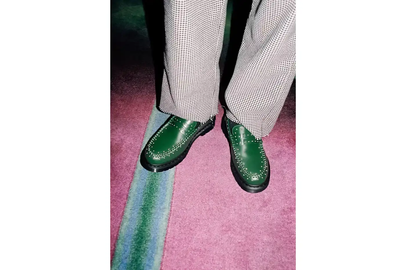 SUPREME TEAMS WITH DR. MARTENS ON EXCLUSIVE PENTON LOAFERS image of the Spring 2025 collaboration between Supreme and Dr. Martens featuring Studded Penton Loafers. The piece describes the three colorways (black, red, and green), the distinctive metal stud detailing around the shoes, co-branded footbeds, and AirWair® cushion soles. Release dates are May 22 for global markets and May 24 for Asian markets, available through Supreme's website and physical stores. The article also briefly mentions Supreme's recent footwear collaborations with Vans and Nike. (image 3 of 5)