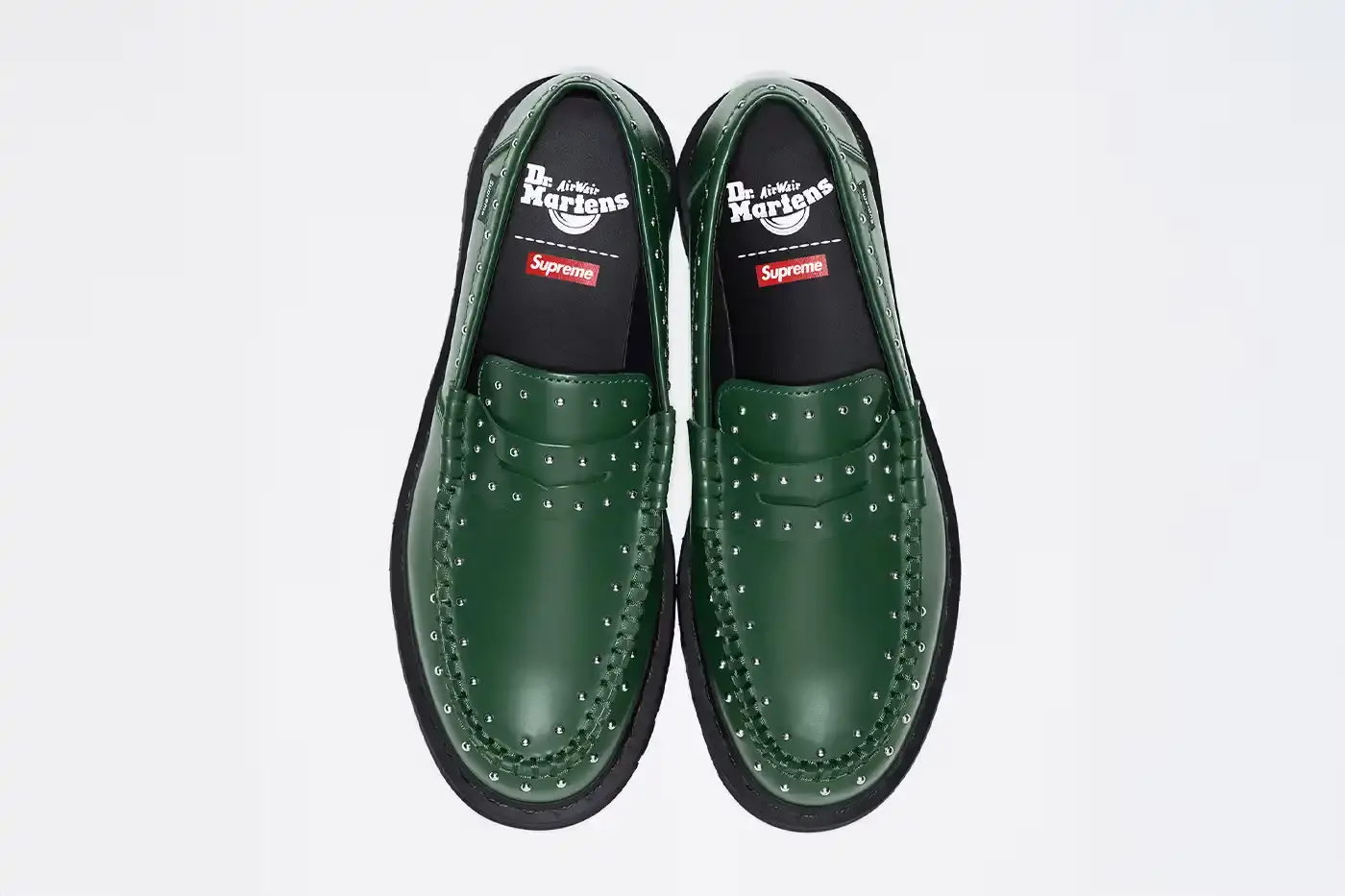 image of the Spring 2025 collaboration between Supreme and Dr. Martens featuring Studded Penton Loafers. The piece describes the three colorways (black, red, and green), the distinctive metal stud detailing around the shoes, co-branded footbeds, and AirWair® cushion soles. Release dates are May 22 for global markets and May 24 for Asian markets, available through Supreme's website and physical stores. The article also briefly mentions Supreme's recent footwear collaborations with Vans and Nike. (image 2 of 3)