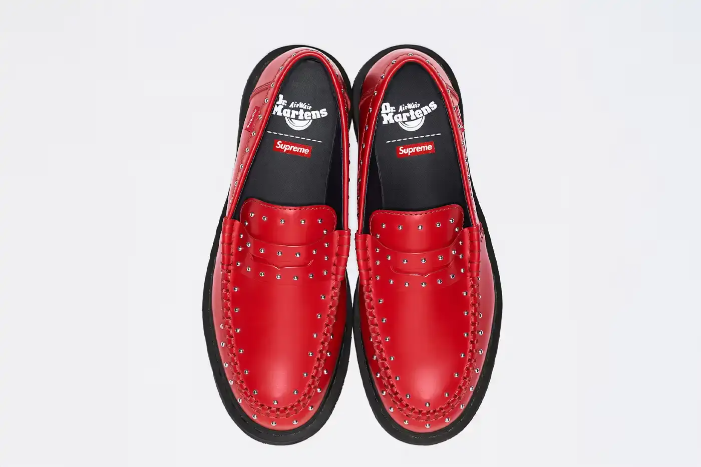 image of the Spring 2025 collaboration between Supreme and Dr. Martens featuring Studded Penton Loafers. The piece describes the three colorways (black, red, and green), the distinctive metal stud detailing around the shoes, co-branded footbeds, and AirWair® cushion soles. Release dates are May 22 for global markets and May 24 for Asian markets, available through Supreme's website and physical stores. The article also briefly mentions Supreme's recent footwear collaborations with Vans and Nike. (image 3 of 3)