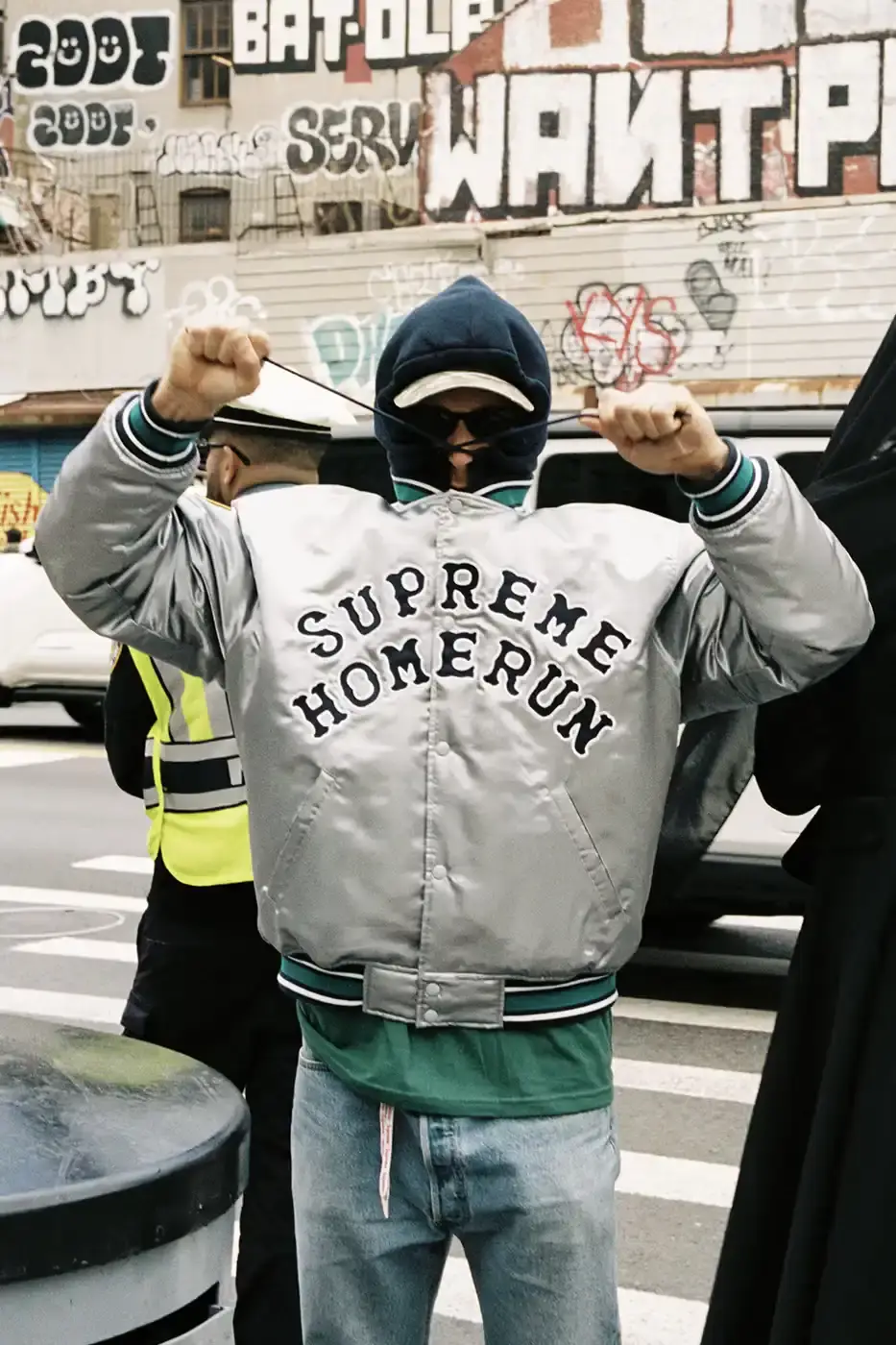 SUPREME PARTNERS WITH HOMERUN FOR BASEBALL-INSPIRED COLLECTION image of the Spring 2025 collaboration between Supreme and Homerun, a brand based in both New York City and Tokyo. The collection features baseball-inspired apparel including varsity jackets in silver and black, baseball jerseys in teal, navy, and pinstriped designs, plus hooded sweatshirts, t-shirts, and New Era caps. All items display co-branding with Homerun's cartoon graphics and "Non Stop" motto. The collection launches May 15 globally and May 17 in Asia through Supreme's website and stores.
