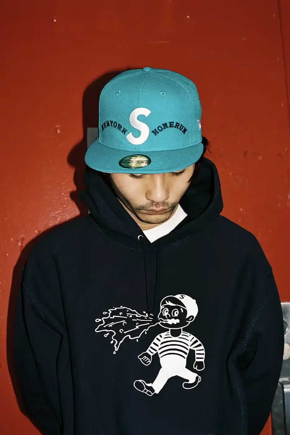SUPREME PARTNERS WITH HOMERUN FOR BASEBALL-INSPIRED COLLECTION image of the Spring 2025 collaboration between Supreme and Homerun, a brand based in both New York City and Tokyo. The collection features baseball-inspired apparel including varsity jackets in silver and black, baseball jerseys in teal, navy, and pinstriped designs, plus hooded sweatshirts, t-shirts, and New Era caps. All items display co-branding with Homerun's cartoon graphics and "Non Stop" motto. The collection launches May 15 globally and May 17 in Asia through Supreme's website and stores. (image 14 of 14)
