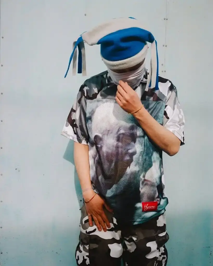 Supreme Supreme x Aphex Twin capsule collection lookbook image showing clothing items featuring iconic Aphex Twin album artwork and logos, including the distinctive logo designed by Paul Nicholson. (image 9 of 10)