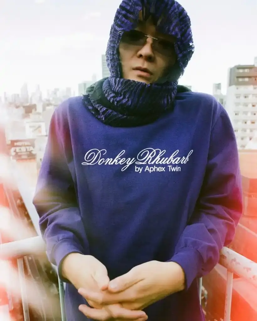 Supreme Supreme x Aphex Twin capsule collection lookbook image showing clothing items featuring iconic Aphex Twin album artwork and logos, including the distinctive logo designed by Paul Nicholson. (image 10 of 10)