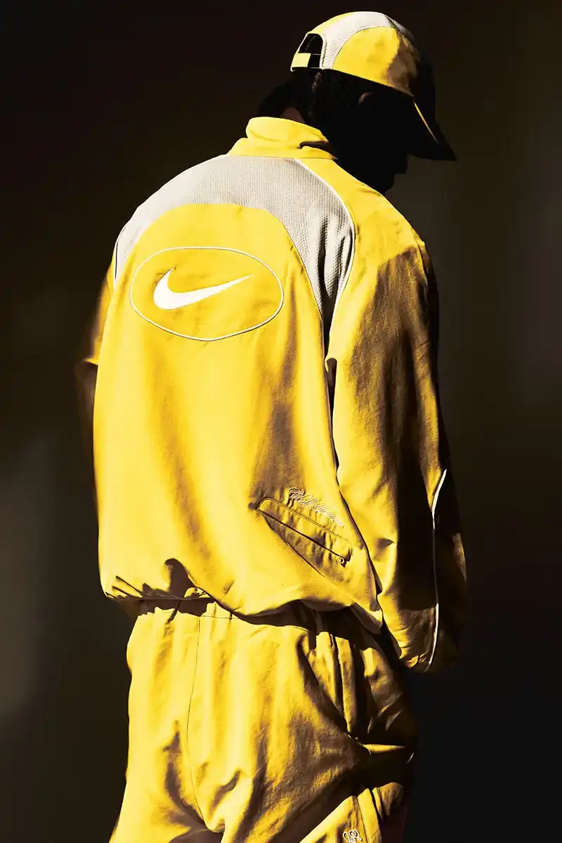 Supreme/Nike Supreme x Nike Spring 2025 Collection featuring black and white Leather Varsity Jackets, purple, yellow and black Track Suits, striped Rugby shirts, Sweater Vests, Hooded Sweatshirts, and accessories including Running Hats and Leather Shoulder Bags. (image 15 of 22)
