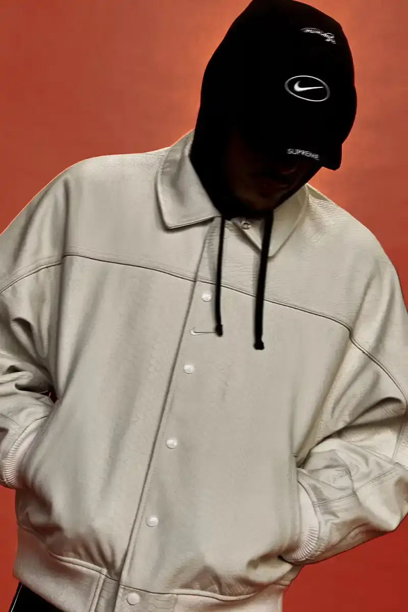 Supreme/Nike Supreme x Nike Spring 2025 Collection featuring black and white Leather Varsity Jackets, purple, yellow and black Track Suits, striped Rugby shirts, Sweater Vests, Hooded Sweatshirts, and accessories including Running Hats and Leather Shoulder Bags. (image 21 of 22)